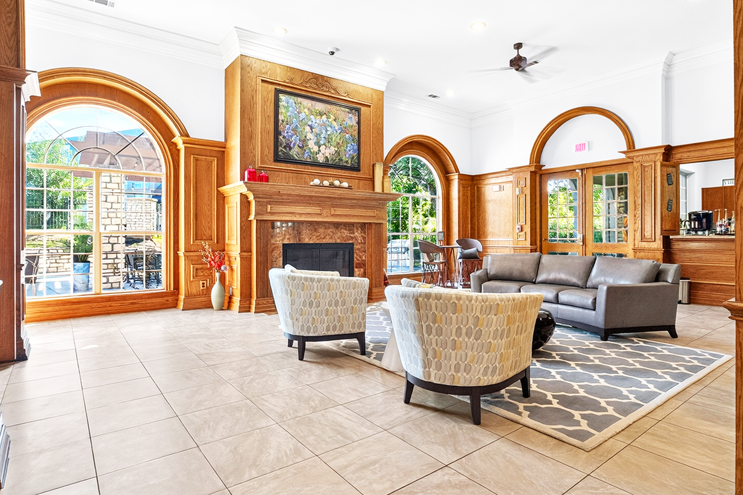 Elegant living room featuring luxurious wooden paneling, cozy fireplace, and stylish furniture with large arched windows providing natural sunlight.
