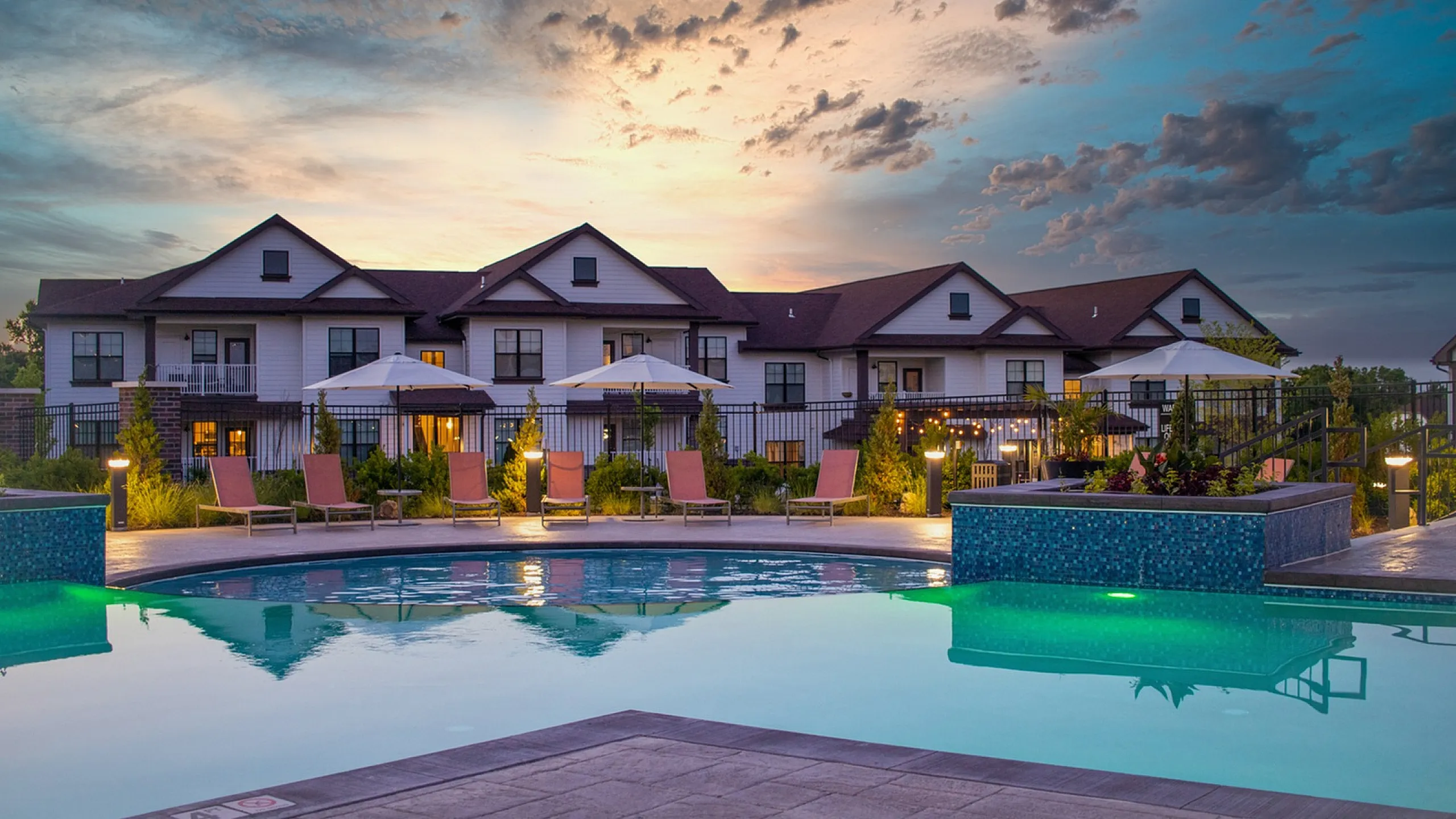 Resort-style swimming pool with lounge seating and apartment building in the background at Meridian at View High Apartments in Lee&rsquo;s Summit, Missouri.