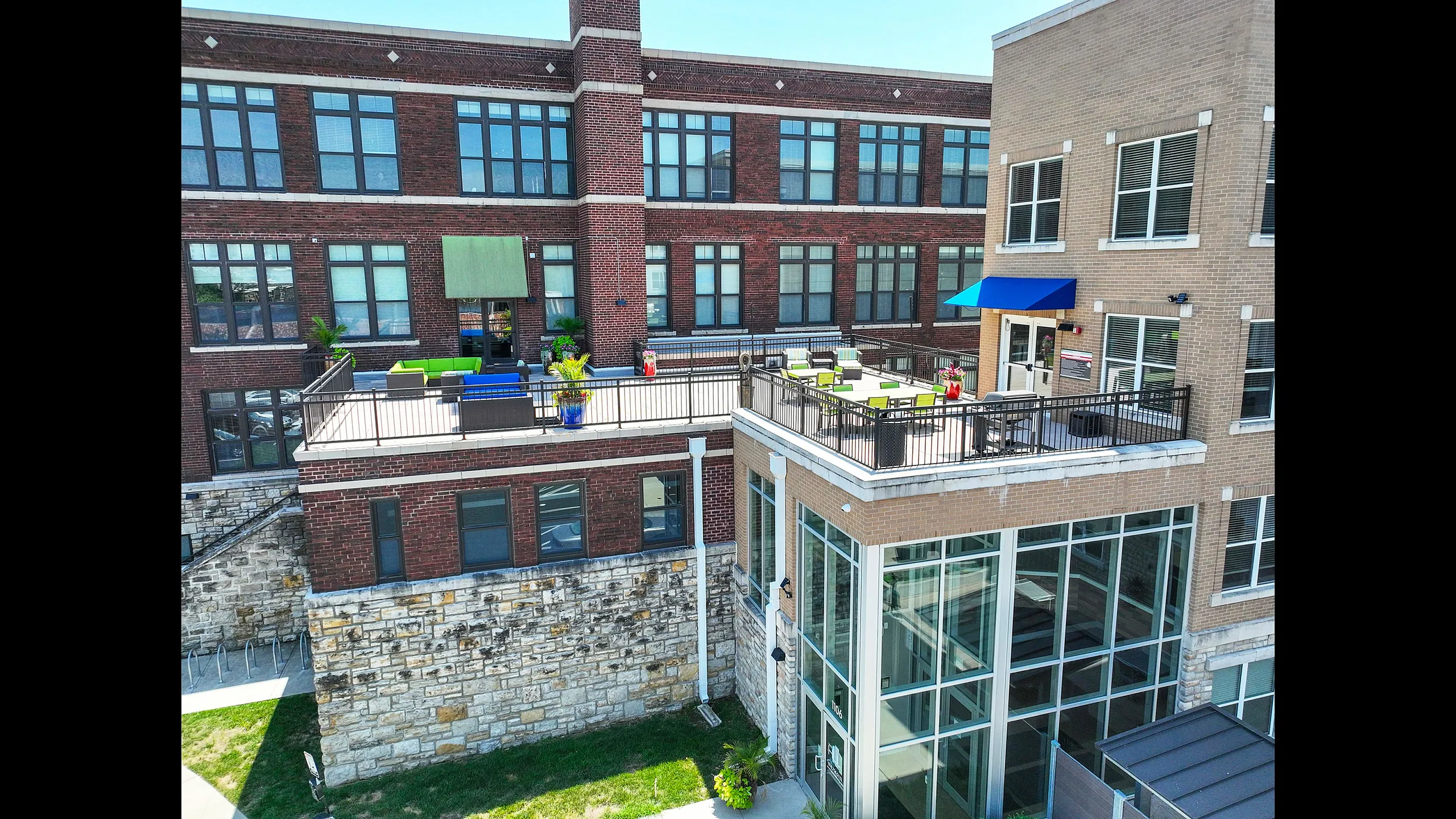 Charming brick apartment building with spacious outdoor terraces adorned with colorful furniture and potted plants.