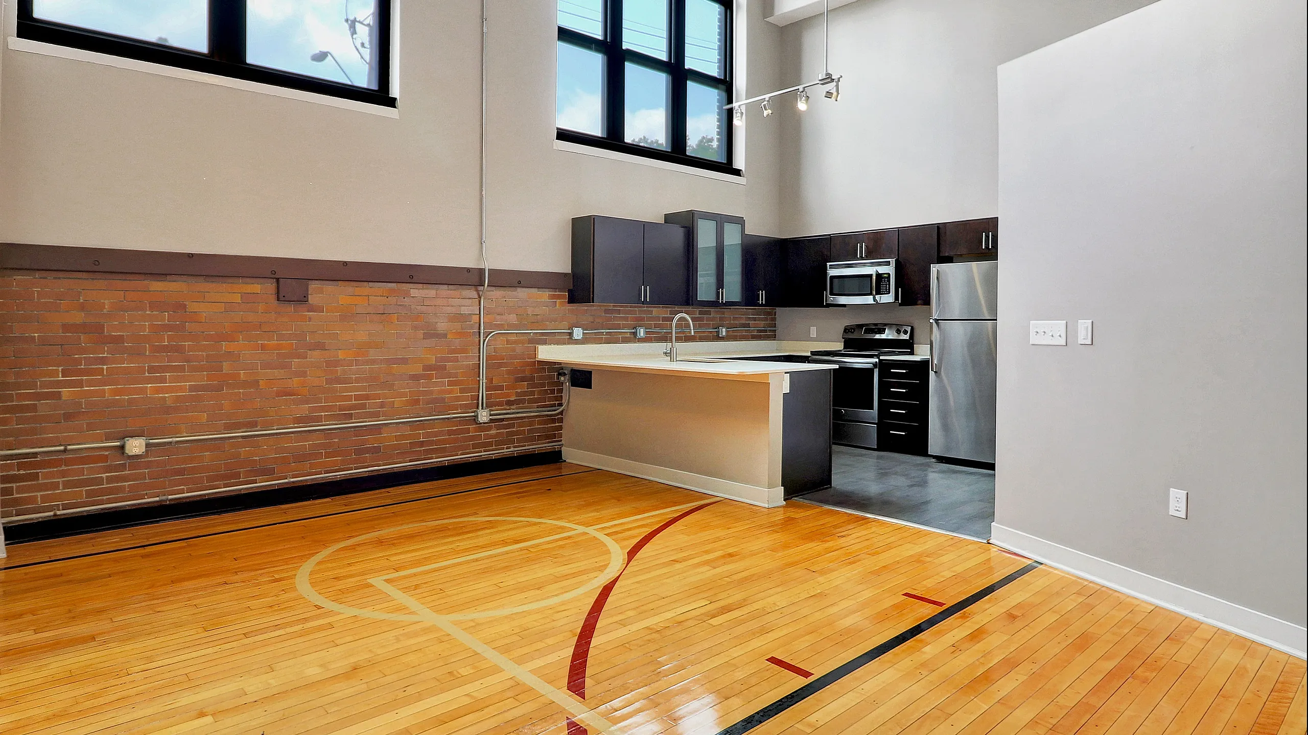 Chic loft kitchen with high ceilings, industrial details, and gleaming wooden floors, featuring modern stainless steel appliances and expansive windows for natural light.