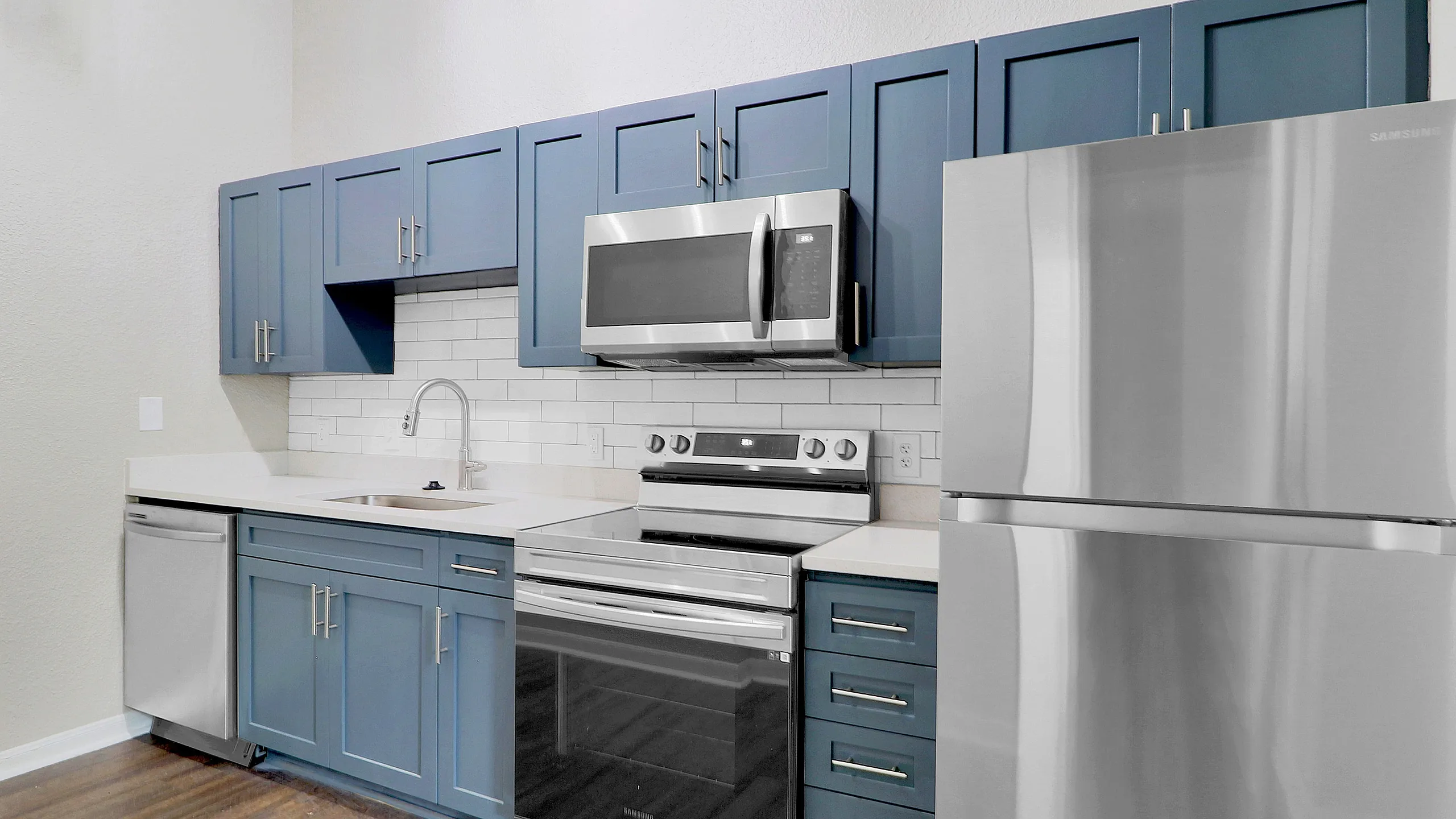 Sleek modern kitchen featuring stylish blue cabinetry, stainless steel appliances, and elegant wood flooring.