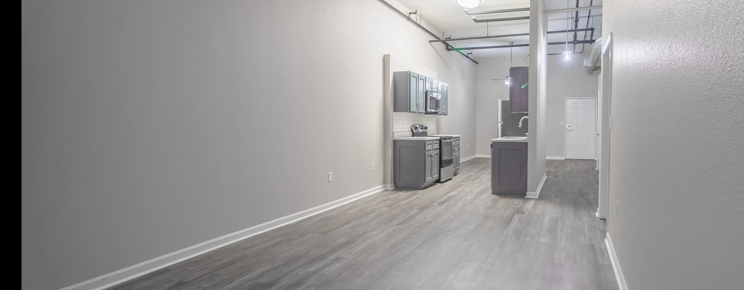 Modern, open-concept apartment with sleek gray flooring and contemporary kitchen design.