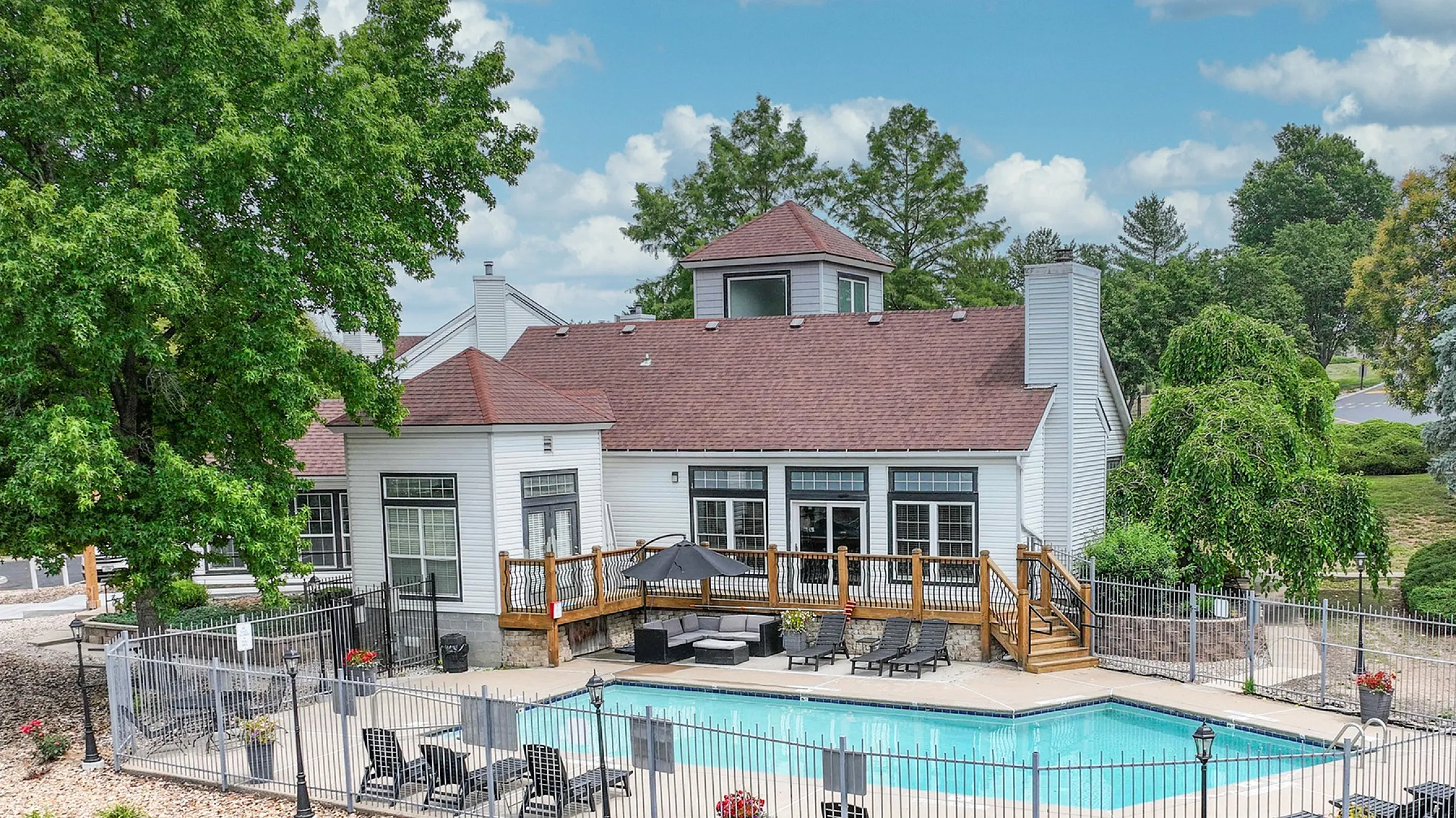 Charming residential complex with a sparkling pool, surrounded by lush greenery and elegant seating area, perfect for relaxation.