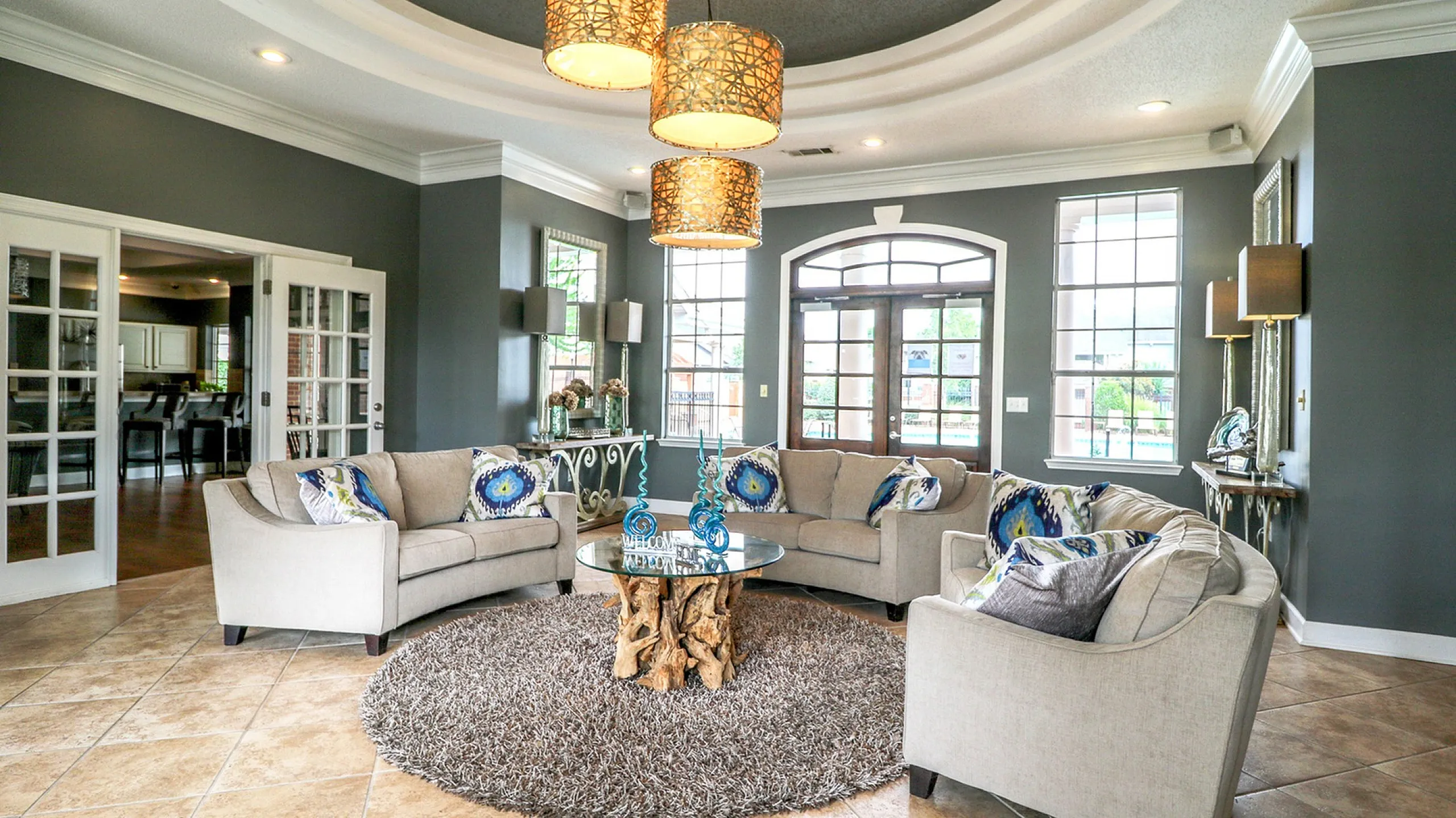 Elegant living room with plush beige sofas, vibrant accent pillows, and large windows offering ample natural light.