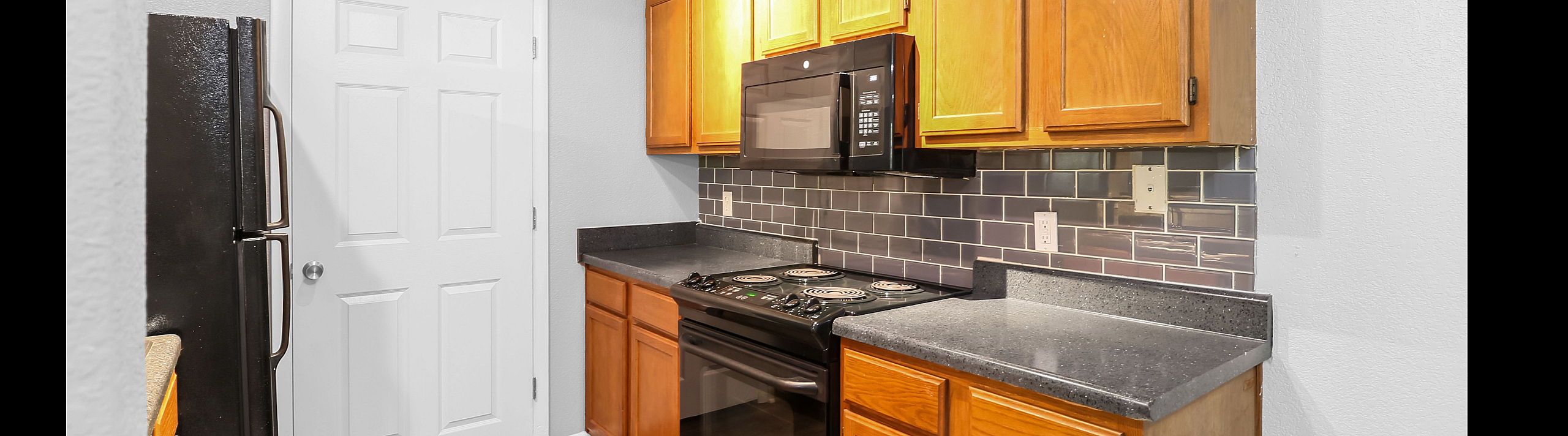 Contemporary kitchen with sleek black appliances, elegant wooden cabinetry, and stylish tile backsplash.