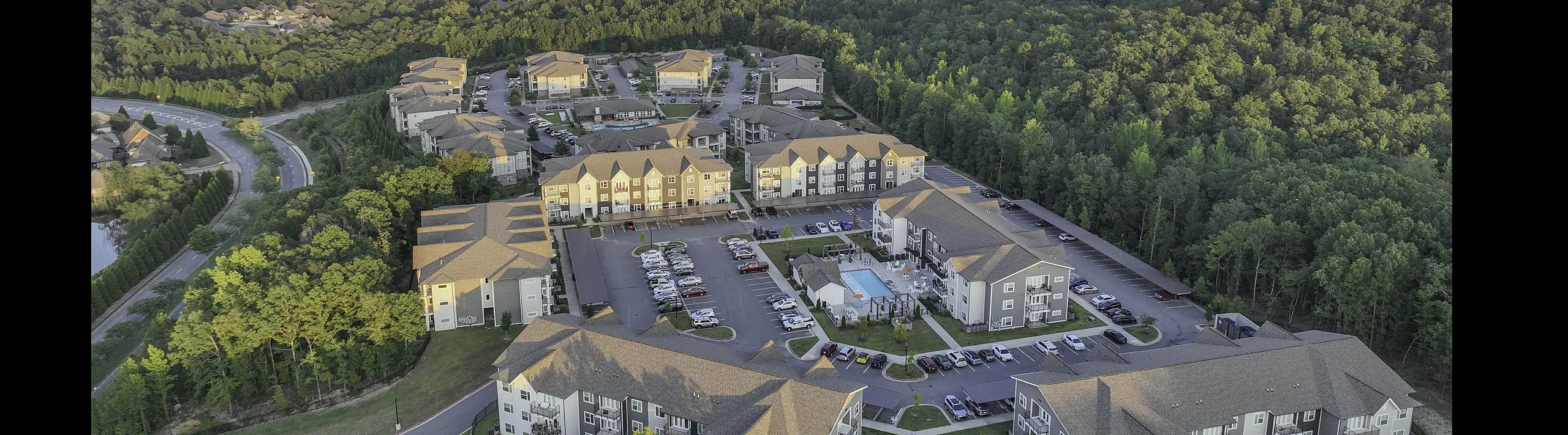 Breathtaking aerial view of a serene apartment complex nestled amidst lush greenery, featuring modern buildings and inviting communal spaces.