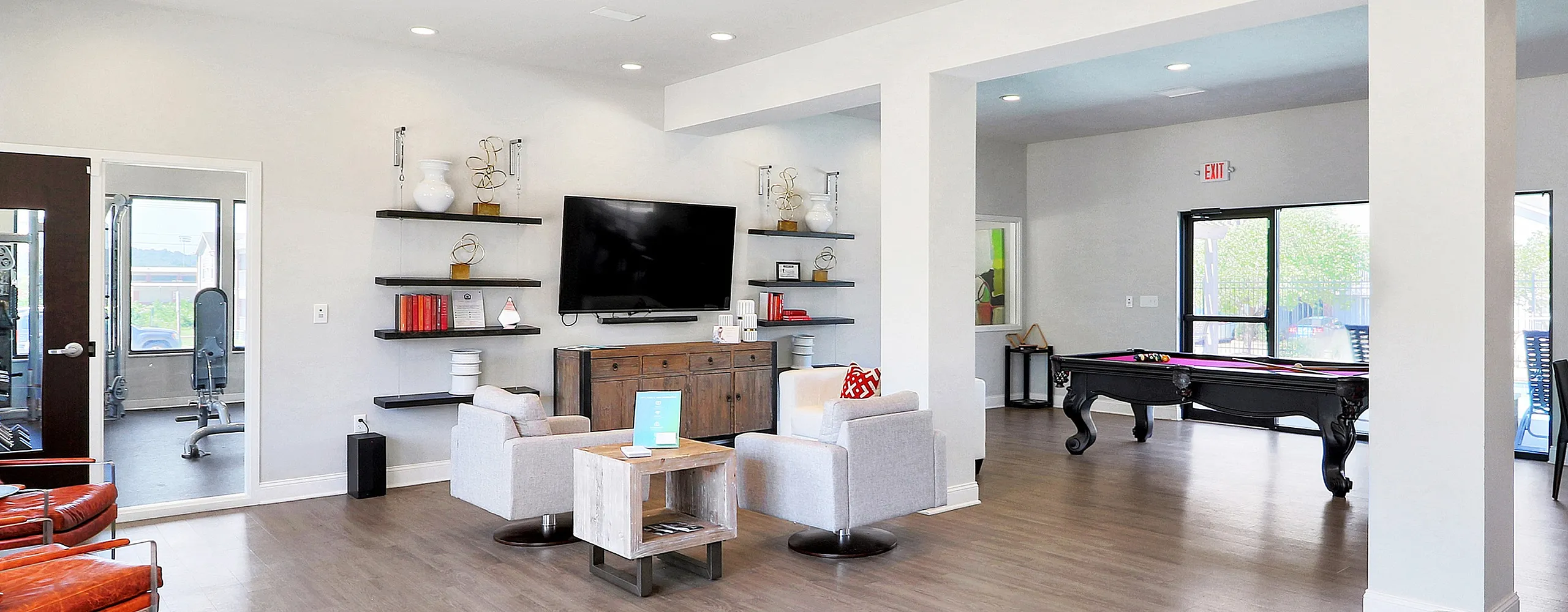 Elegant communal lounge with cozy seating, wall-mounted TV, chic shelving, and a vibrant pool table area, offering a stylish space for relaxation and entertainment.