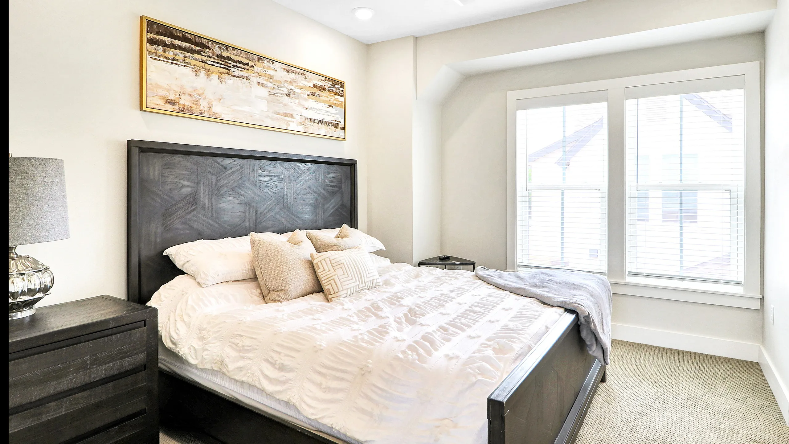 Inviting bedroom with a luxurious bed, stylish decor, and ample natural light through large windows.