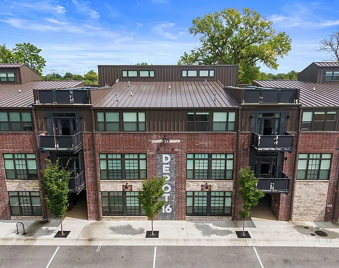 Charming urban apartment complex featuring modern brick facade and inviting balconies under a clear blue sky.