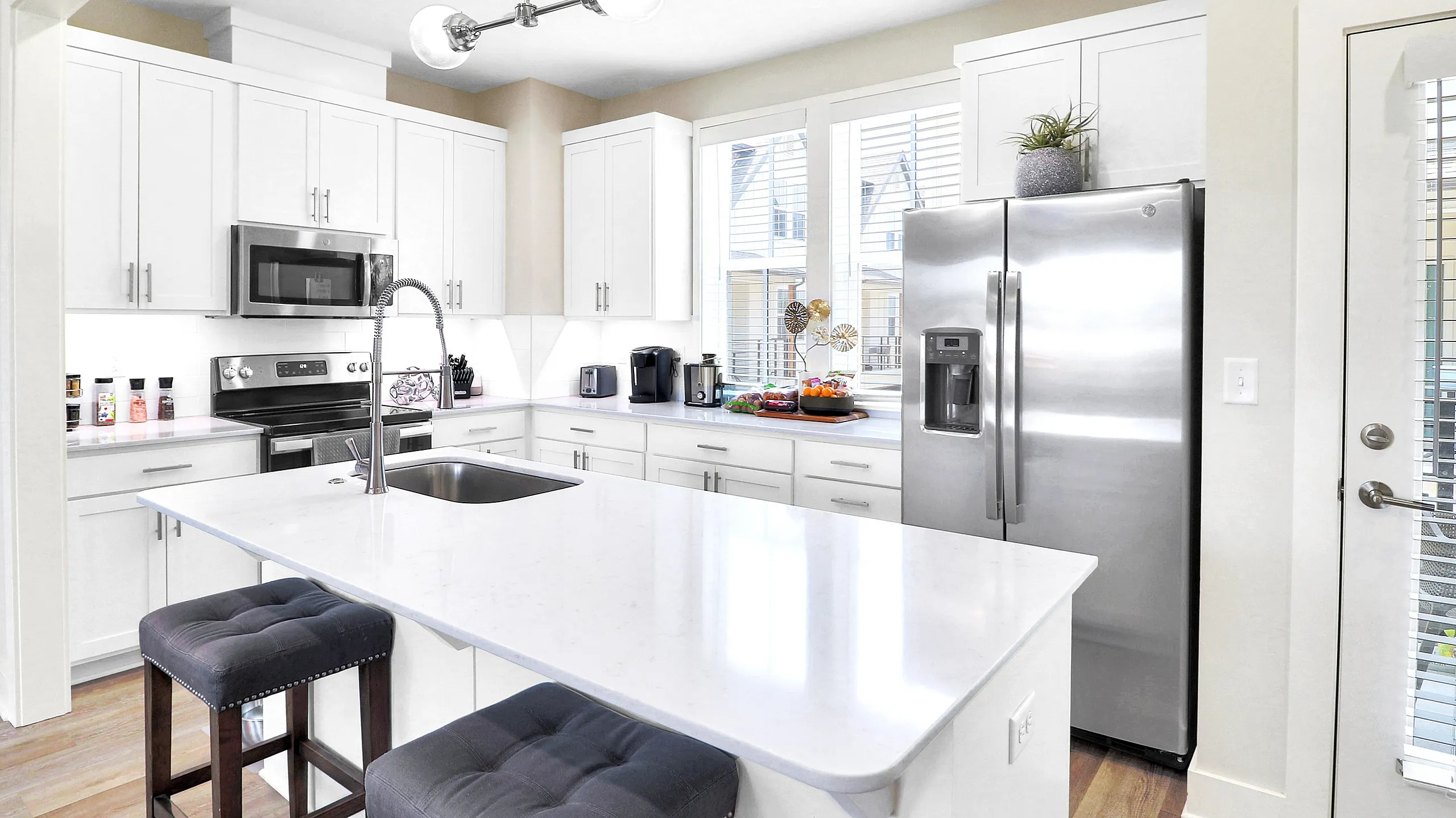 Modern kitchen with sleek white cabinetry, stainless steel appliances, and a spacious island with chic bar stools.