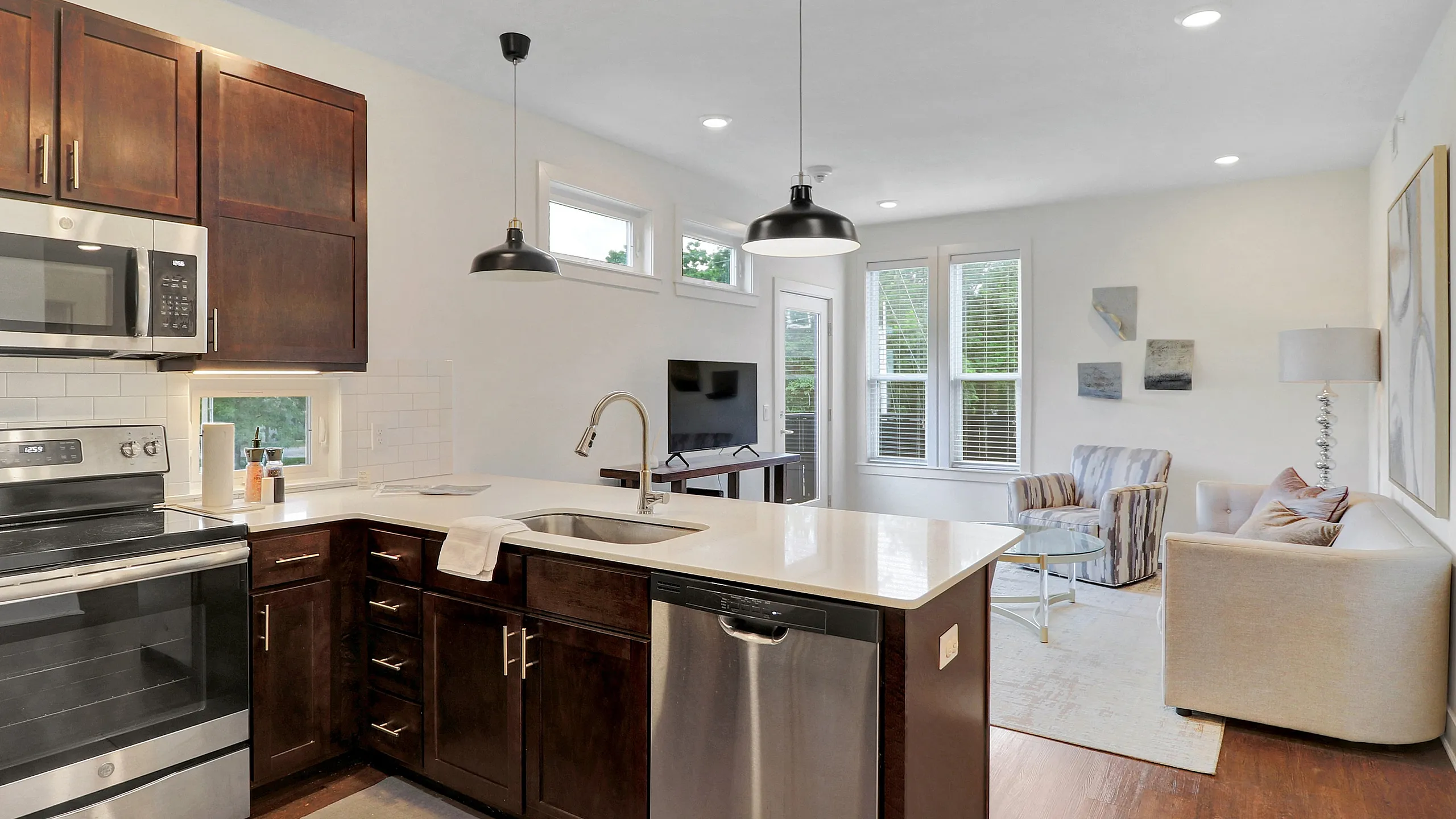 Modern apartment showcasing a bright open-concept kitchen and living area, featuring sleek appliances and elegant furnishings.