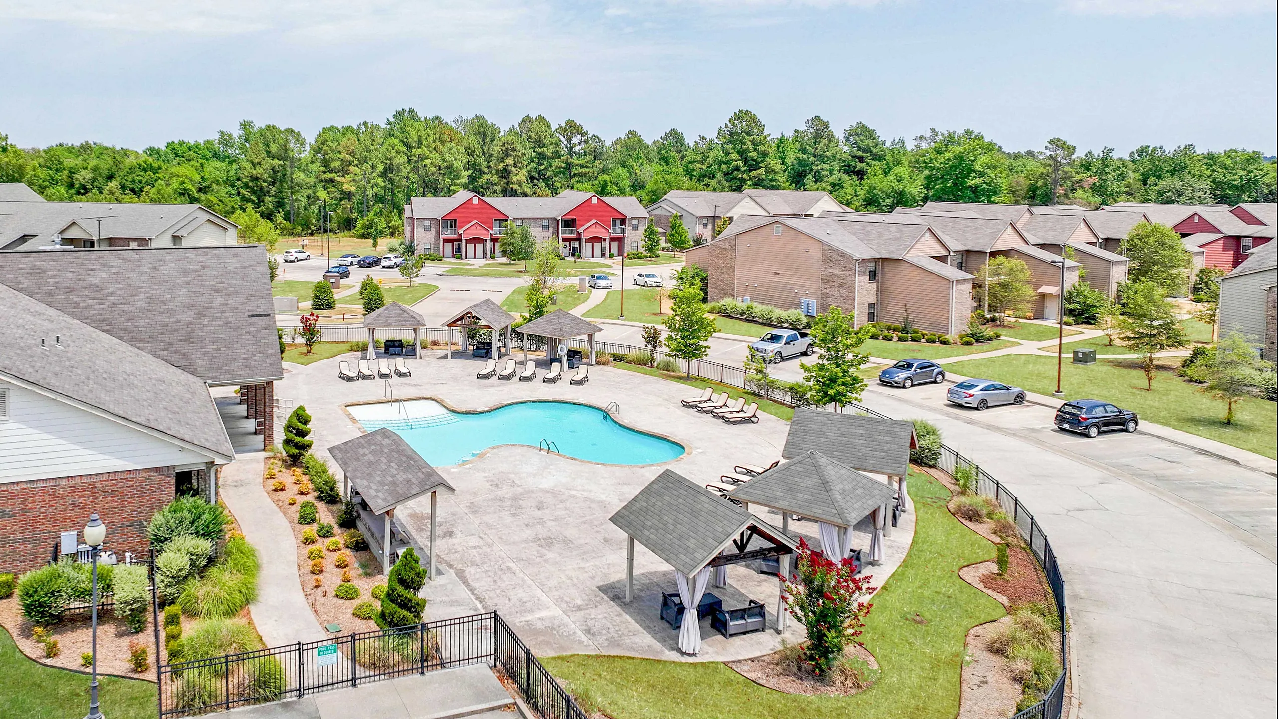 Inviting apartment complex with a pristine pool, stylish cabanas, and lush landscaping surrounded by modern townhouses, perfect for a serene living experience.