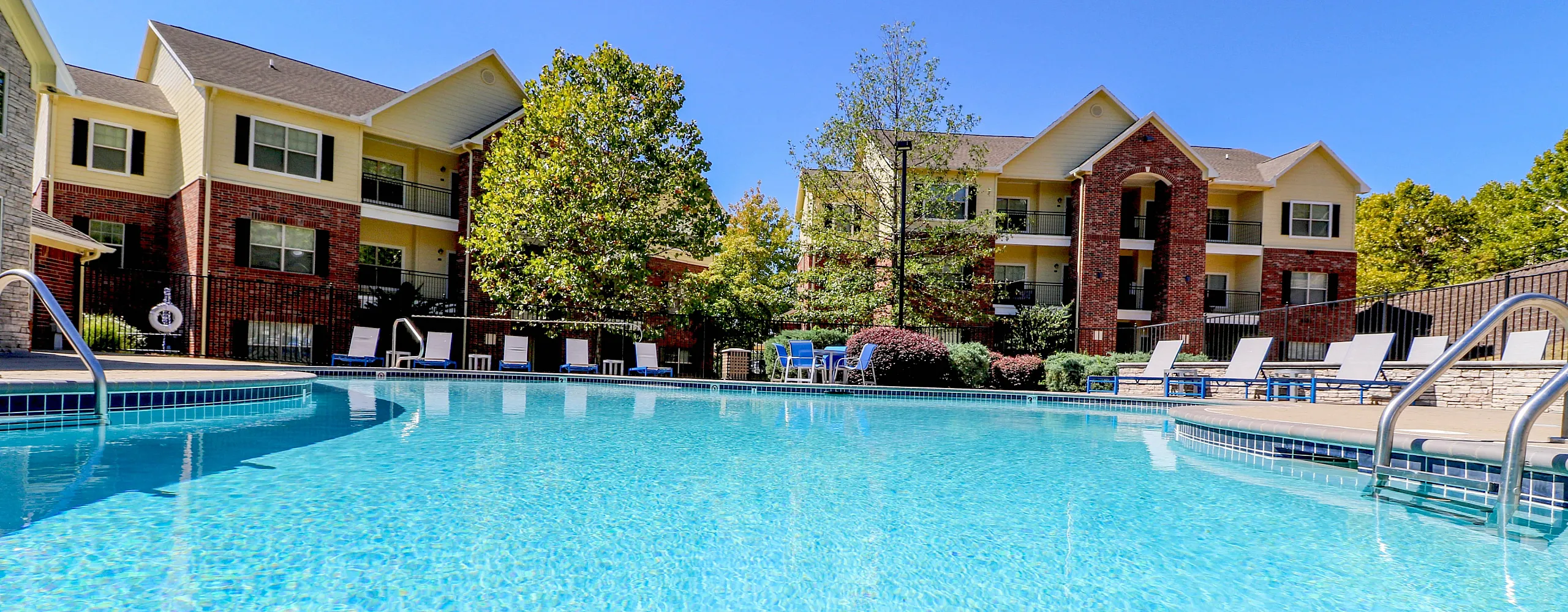 Luxurious apartment complex with sparkling pool, surrounded by elegant buildings and lush greenery, perfect for relaxation and leisure.