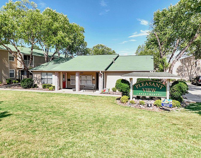 Charming apartment complex with green roofs, surrounded by lush greenery and well-manicured lawns, offering a welcoming atmosphere at Pleasant View Apartments.