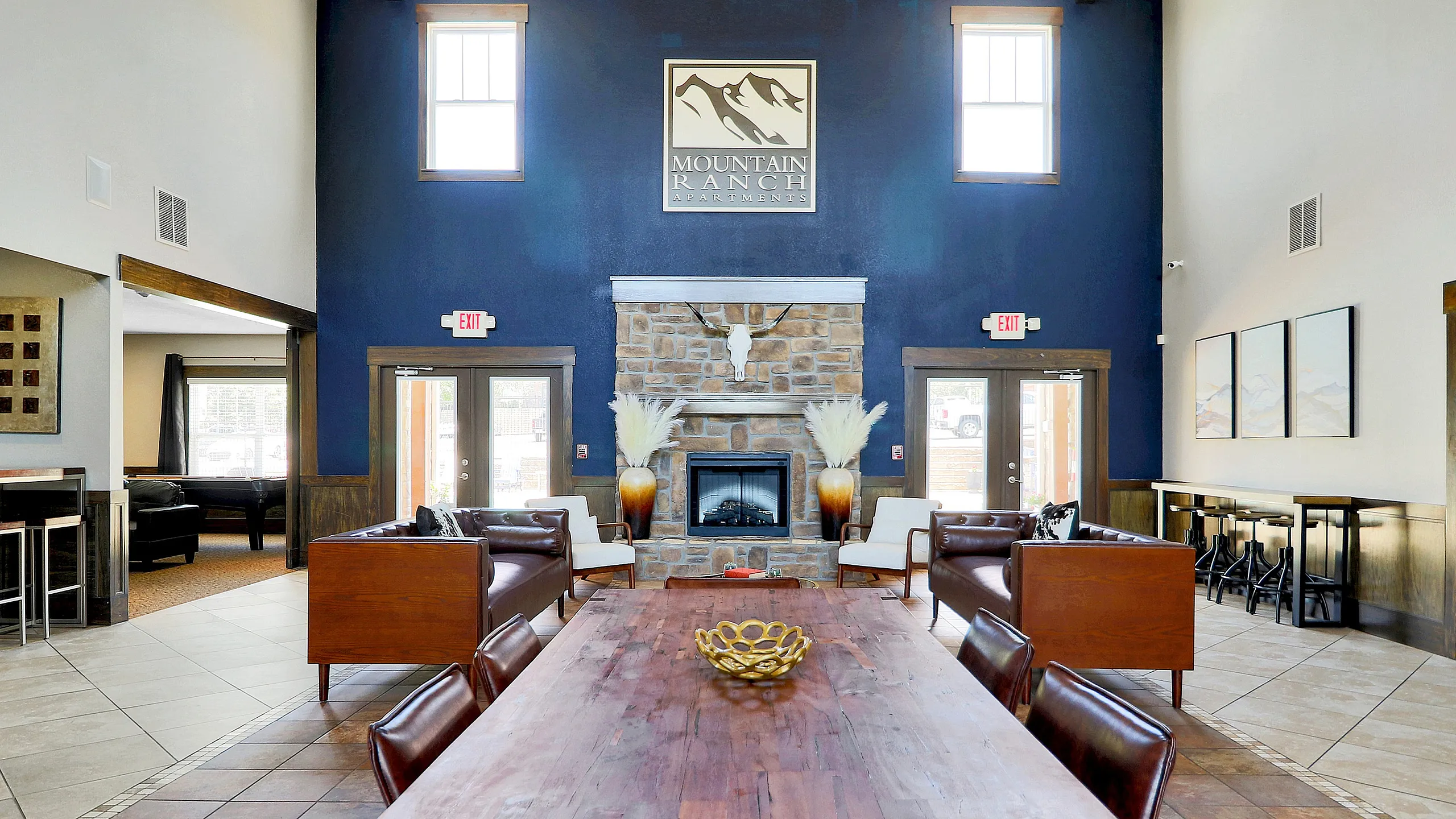 Elegant apartment lobby featuring a rustic stone fireplace, high ceilings, and stylish seating areas with contemporary decor.