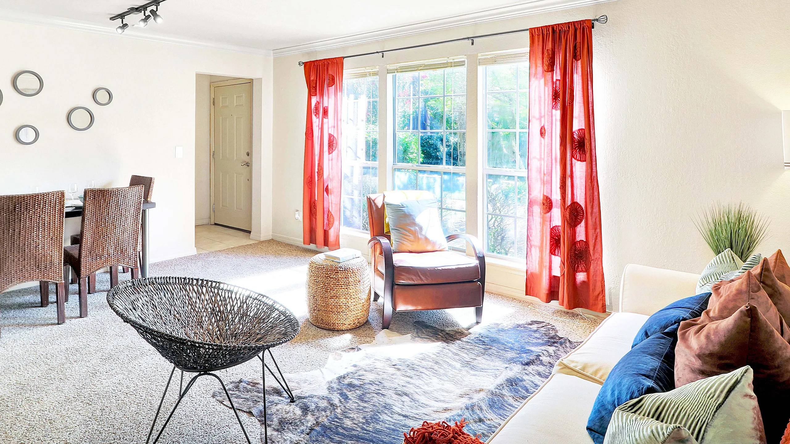 Bright, cozy living area with modern decor, featuring large windows with vibrant red curtains, a comfortable seating arrangement, and a stylish dining space.