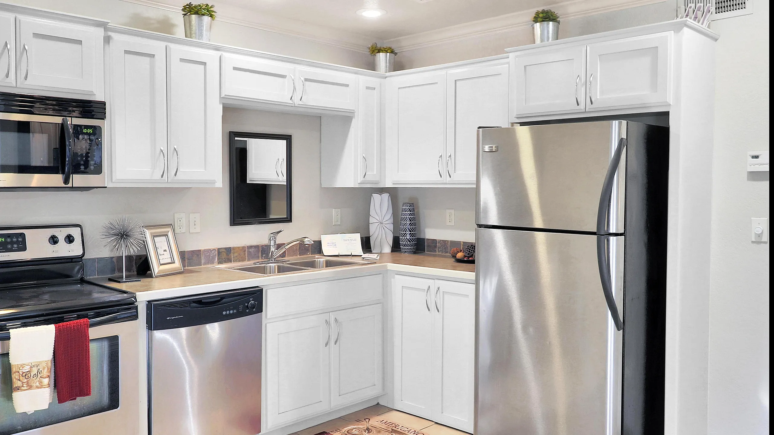 Modern kitchen with sleek stainless steel appliances, white cabinetry, and elegant tile backsplash.