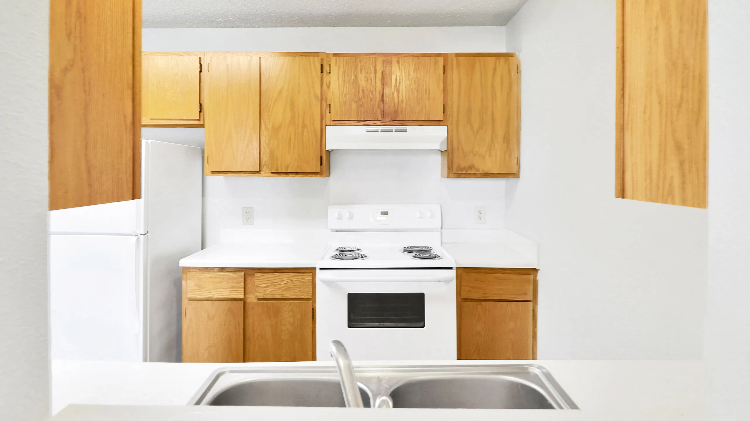 Bright kitchen with sleek white countertops, modern stove, and ample wood cabinetry offering warm and inviting functionality.
