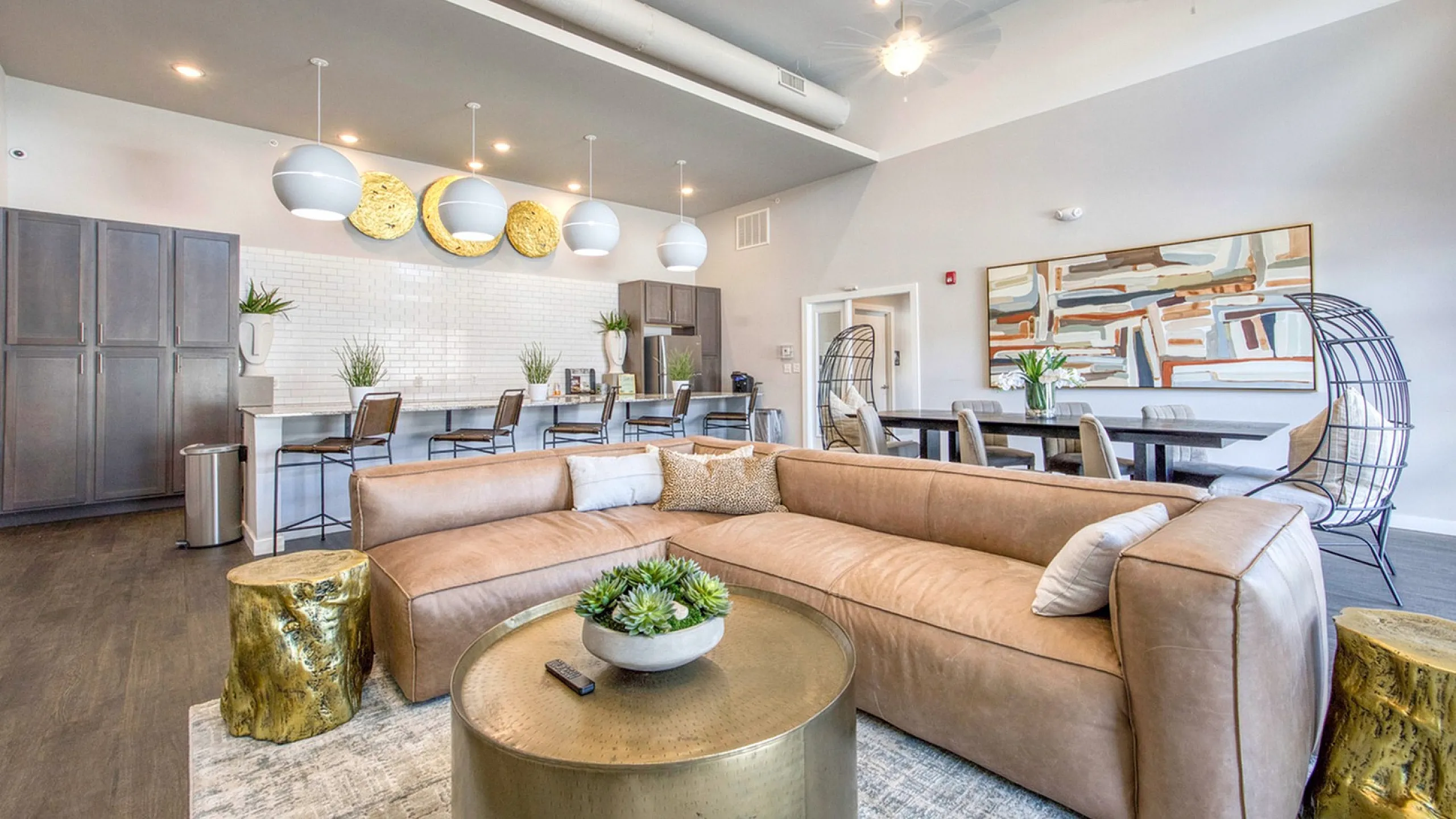 Luxurious open-plan living space featuring modern decor, elegant lighting, a stylish kitchen bar area, and a cozy leather sofa.
