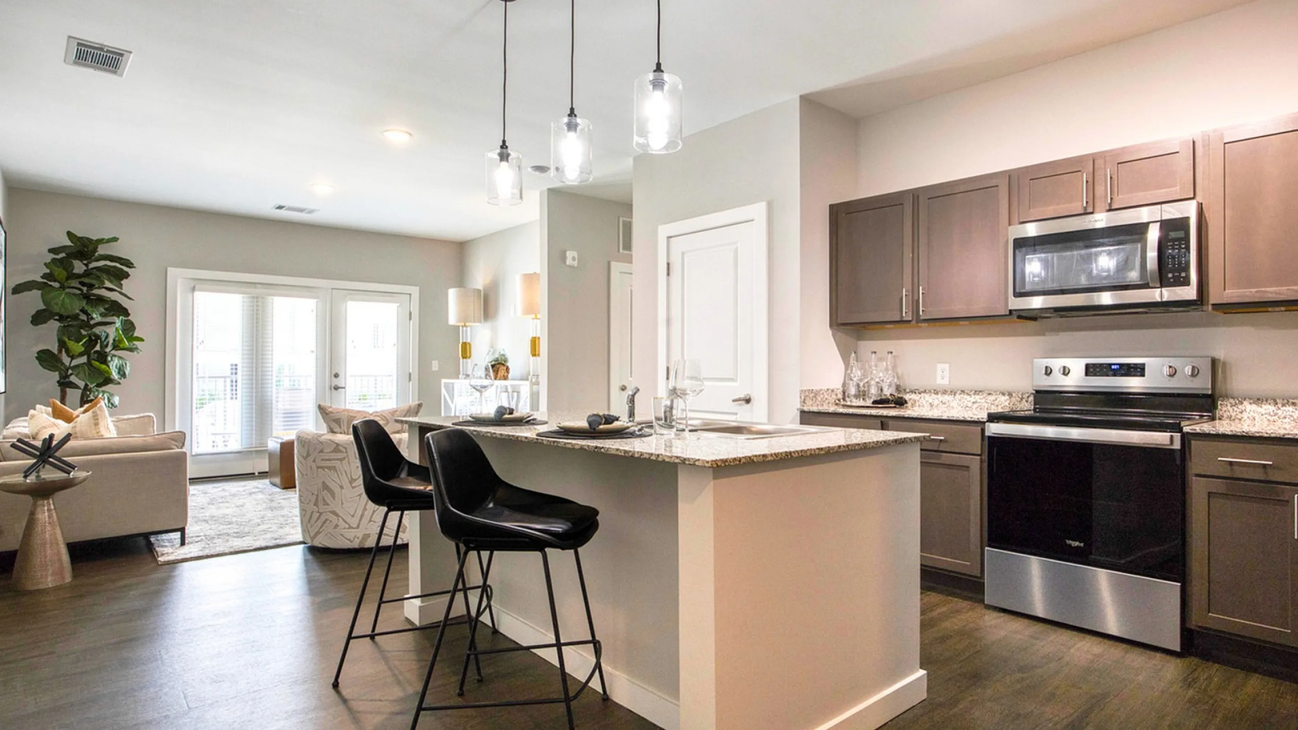 Bright open-concept kitchen and living area with modern appliances, stylish pendant lighting, and cozy seating space.