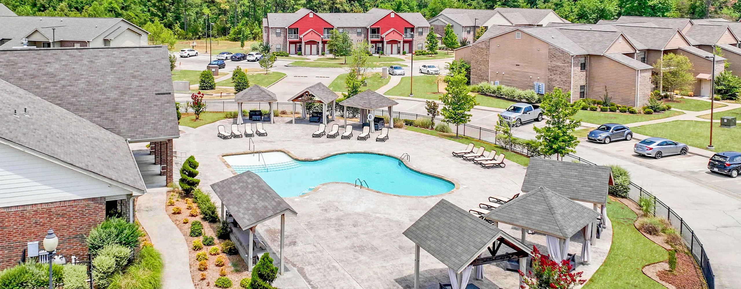 Charming apartment complex featuring a sparkling swimming pool with cozy cabanas and lush landscaping, perfect for relaxation and leisure.