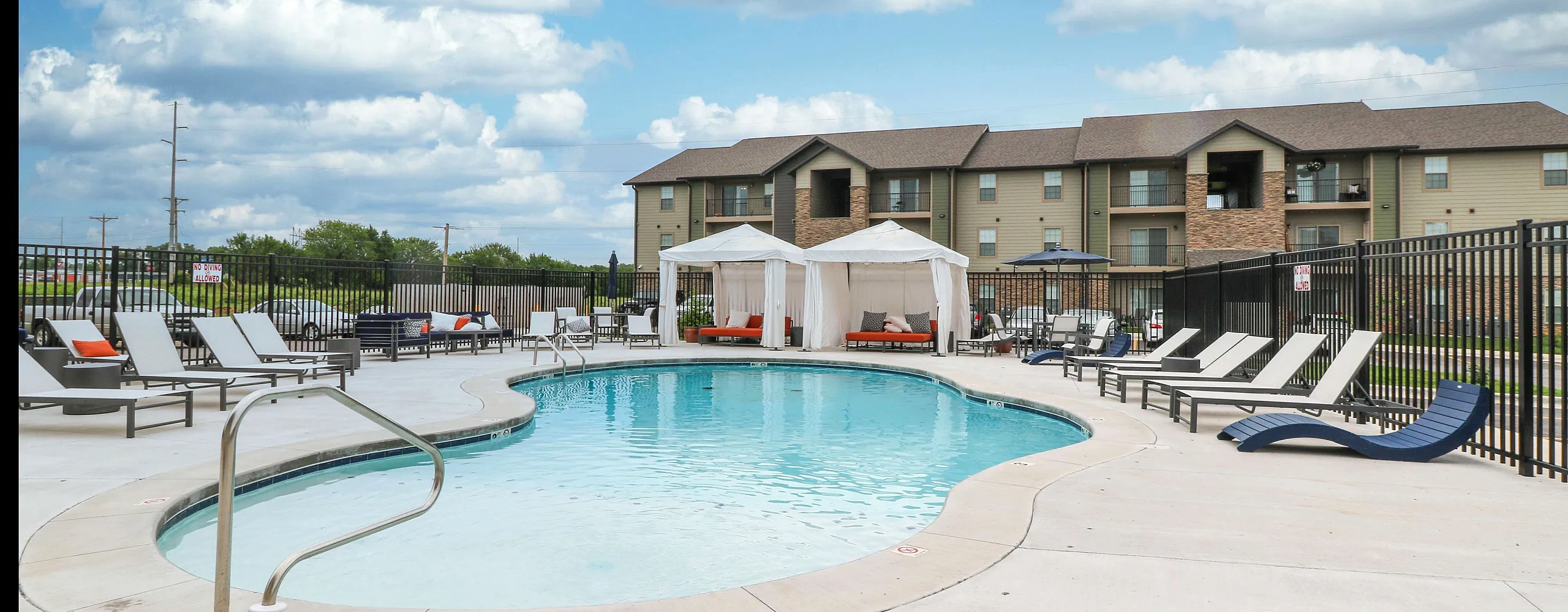 Inviting outdoor pool area with elegant cabanas and stylish lounge chairs, perfect for relaxation in a modern apartment complex.