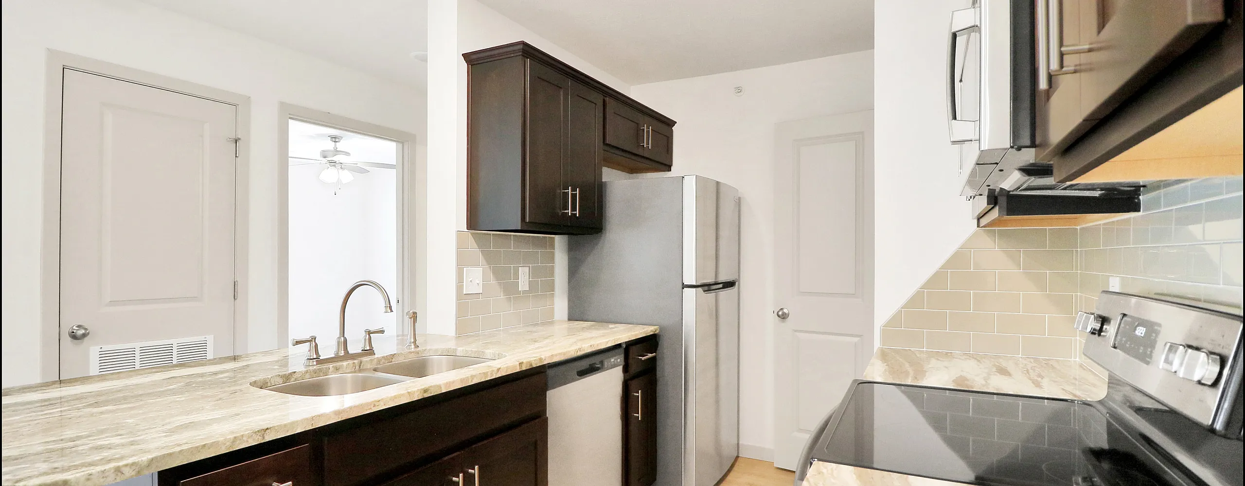 Modern kitchen with elegant marble countertops, stainless steel appliances, and dark wood cabinetry, perfect for a contemporary home.
