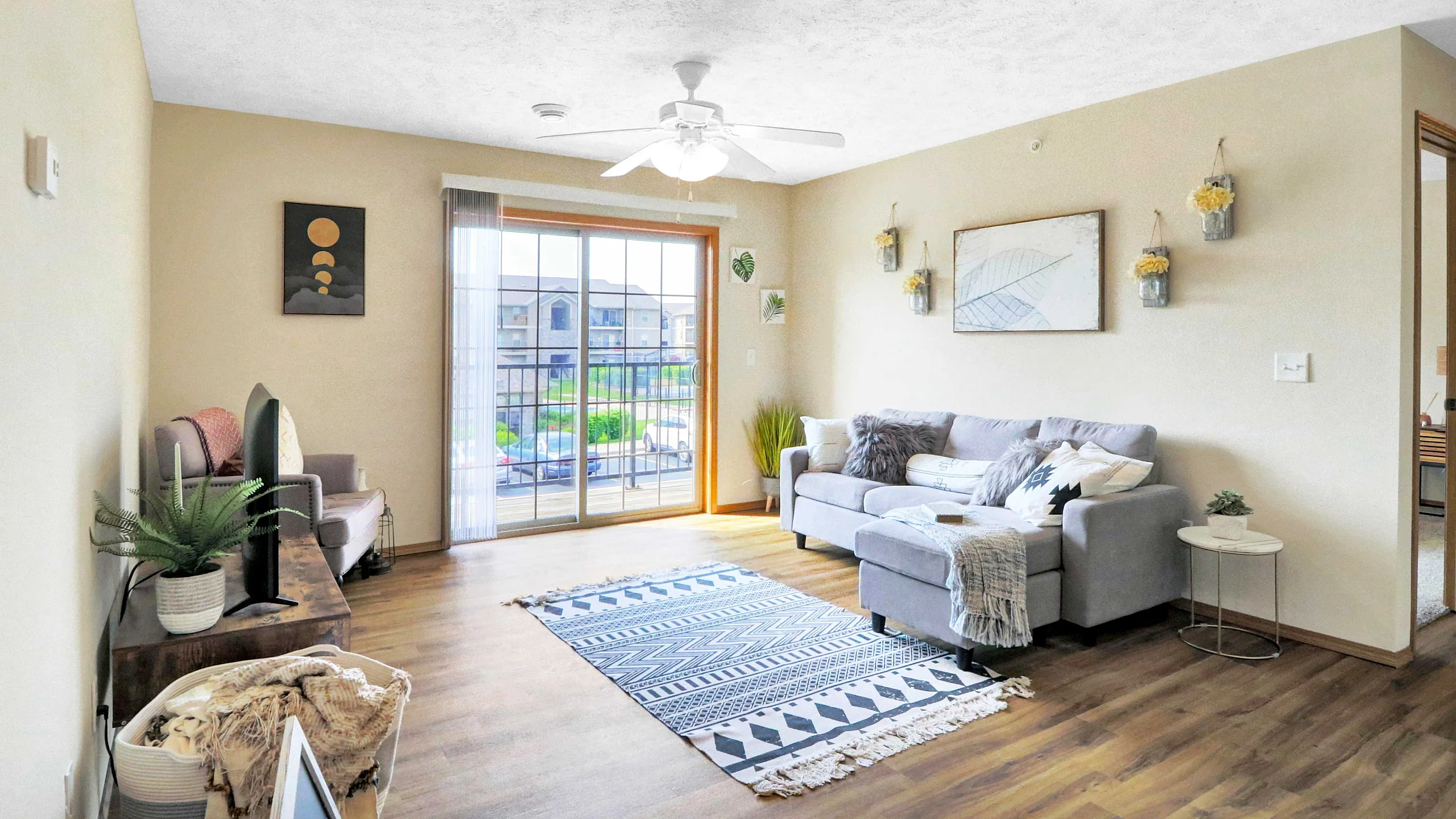 Bright and inviting living room with modern gray sofa, stylish decor, and large sliding doors opening to a scenic balcony view.