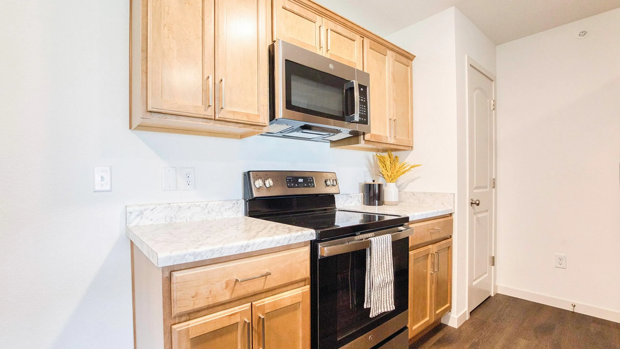 Bright and modern kitchen with sleek stainless steel appliances, elegant wooden cabinets, and stylish marble countertops.