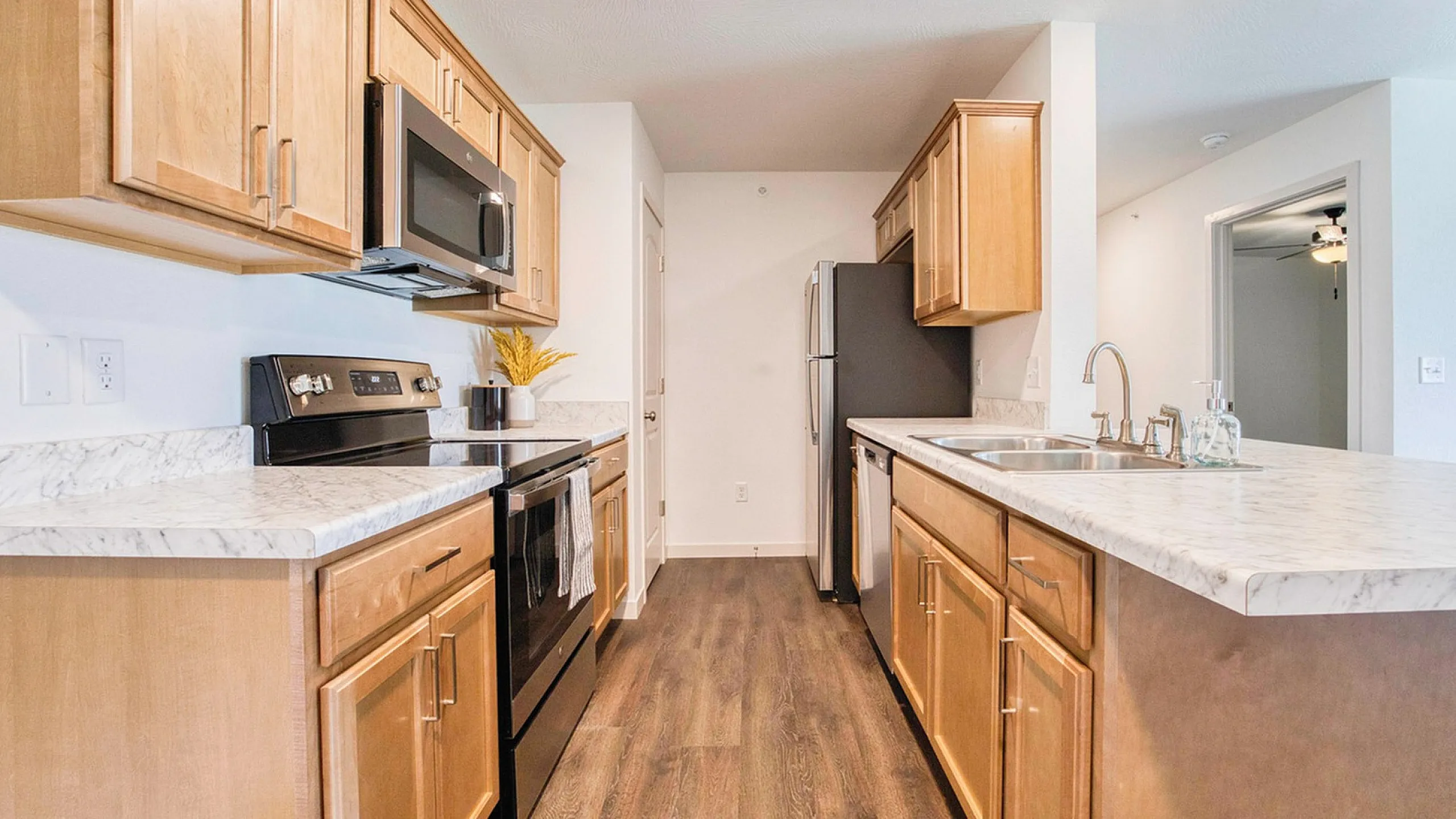 Modern kitchen with sleek stainless steel appliances, elegant marble countertops, and warm wooden cabinetry, offering a perfect blend of style and functionality.