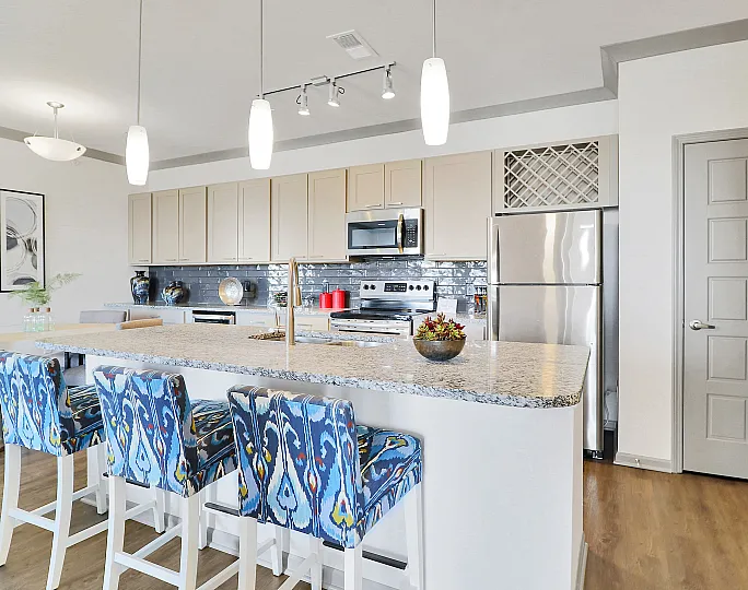 Chic modern kitchen with a spacious granite island, stylish blue patterned bar stools, and stainless steel appliances for a sleek, inviting space.