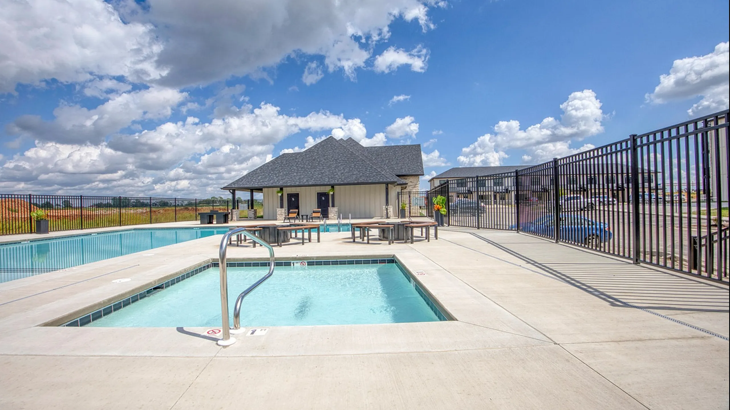 Inviting outdoor pool area with a clear blue sky backdrop, featuring a cozy pool house and ample seating for relaxation.