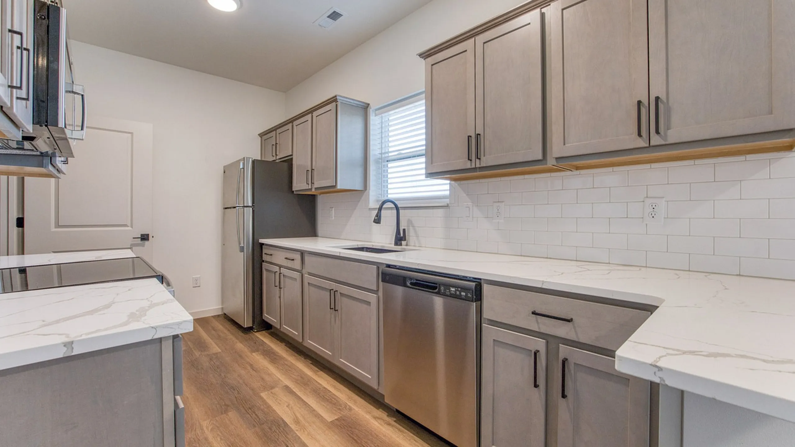 Modern kitchen featuring sleek stainless steel appliances, elegant marble countertops, and rich wooden cabinets with a chic, contemporary design.
