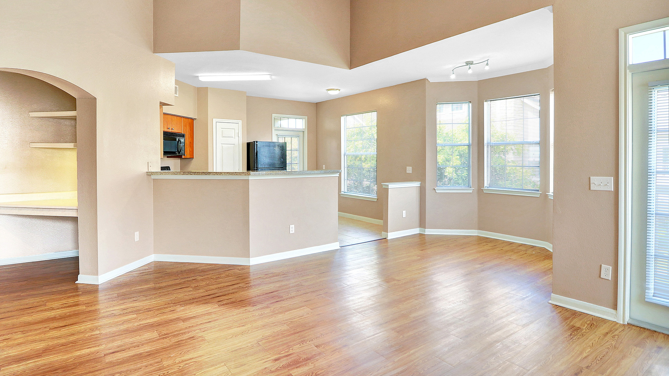 Bright open-concept living area with elegant hardwood floors, abundant natural light, and a modern kitchen featuring sleek cabinetry.