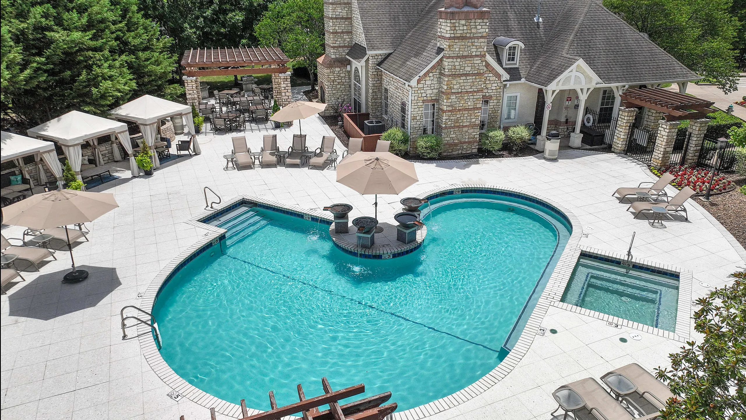Luxurious apartment exterior featuring a crystal-clear swimming pool surrounded by stylish lounge chairs and elegant cabanas.