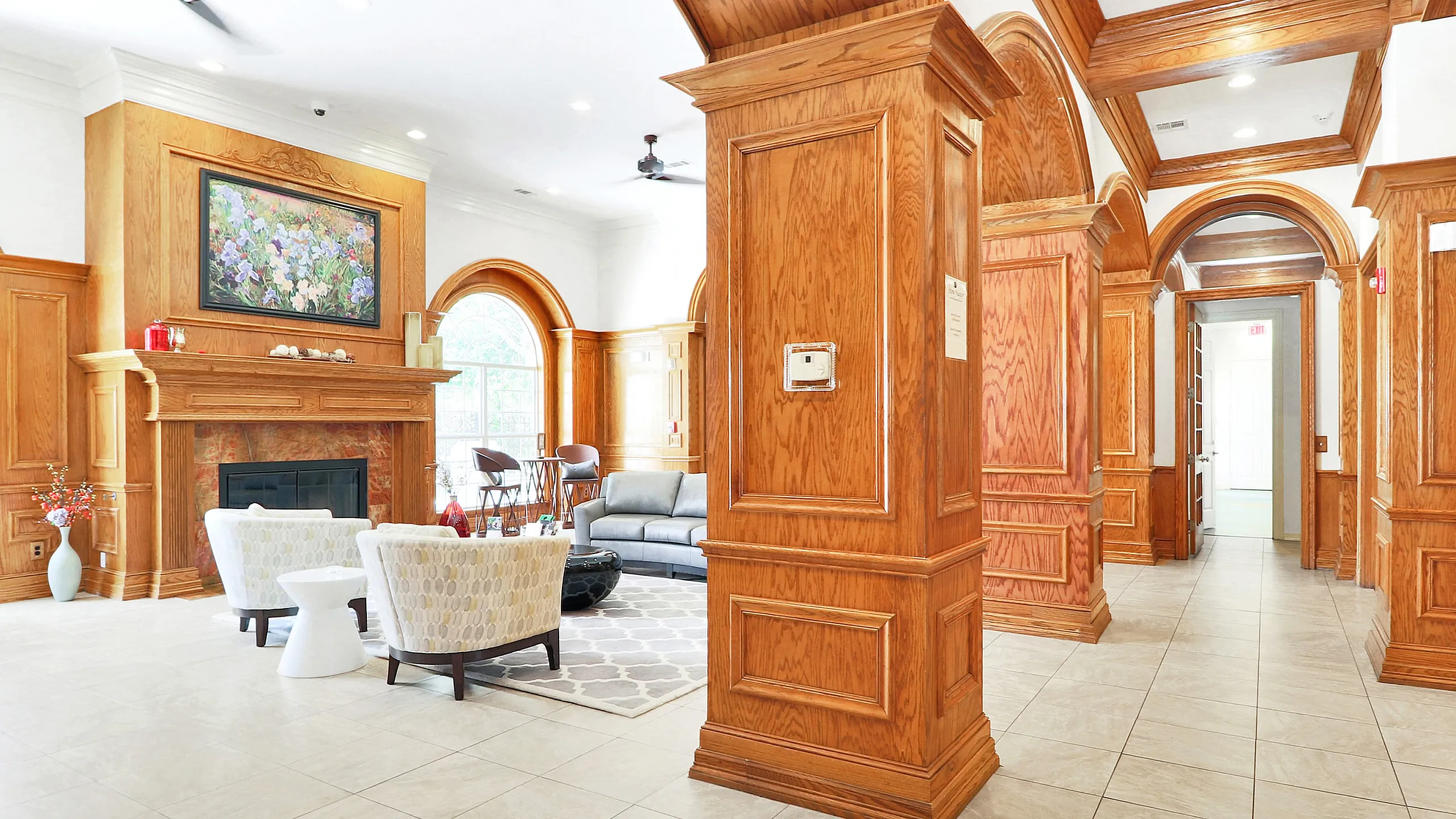 Elegant living space featuring warm wooden finishes, inviting seating area, and a sophisticated fireplace with a floral painting above.