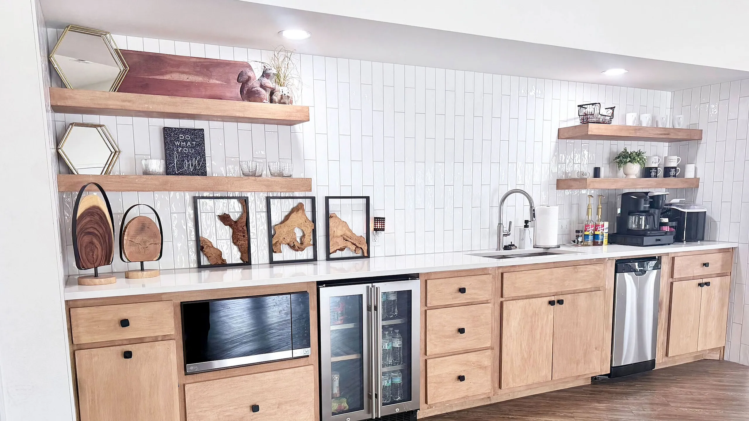 Modern kitchen with sleek white tile backsplash, wooden cabinetry, open shelving, and stainless steel appliances.