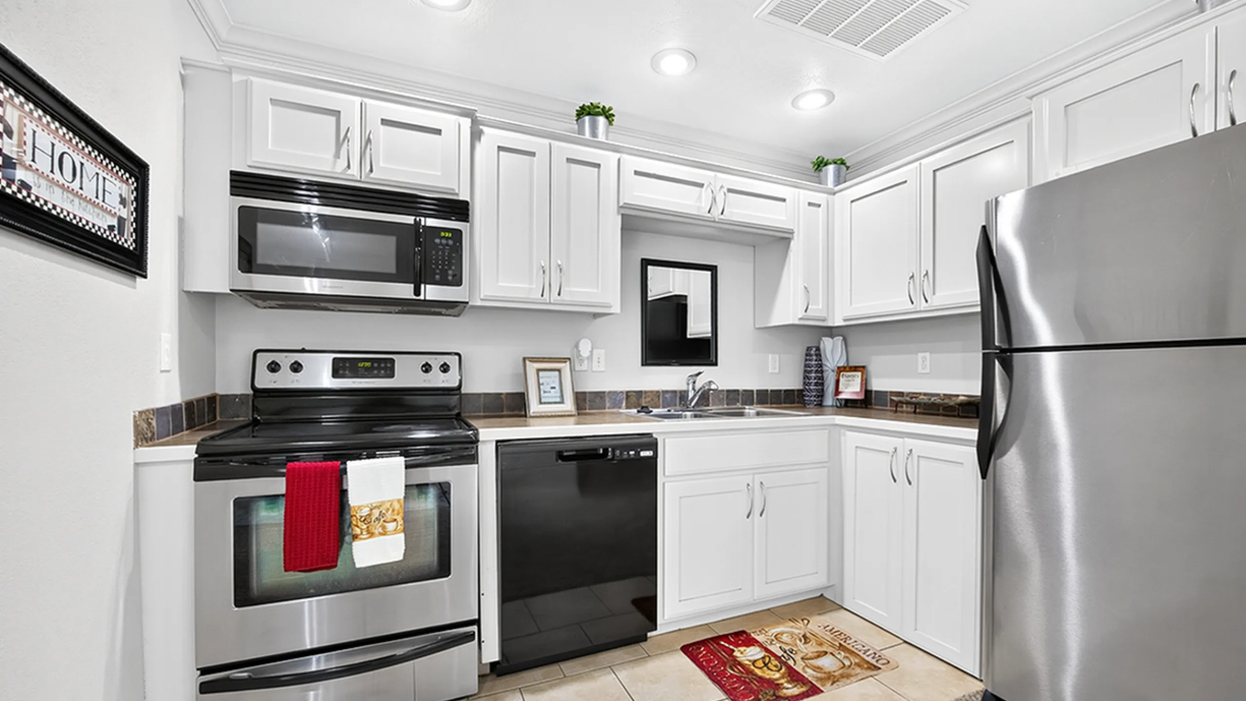 Modern kitchen with sleek stainless steel appliances, pristine white cabinetry, and elegant tile flooring, offering a stylish and functional culinary space.