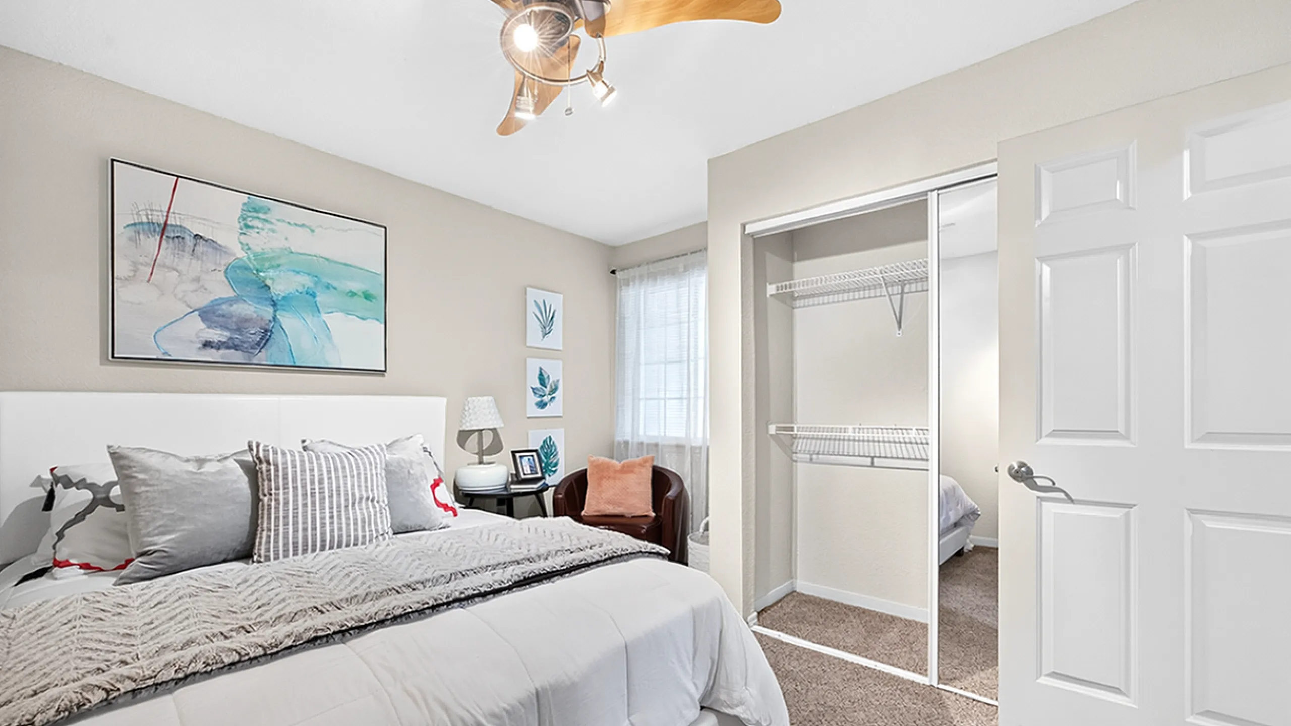 Bright, inviting bedroom with modern decor, featuring a cozy bed, stylish ceiling fan, and spacious closet.