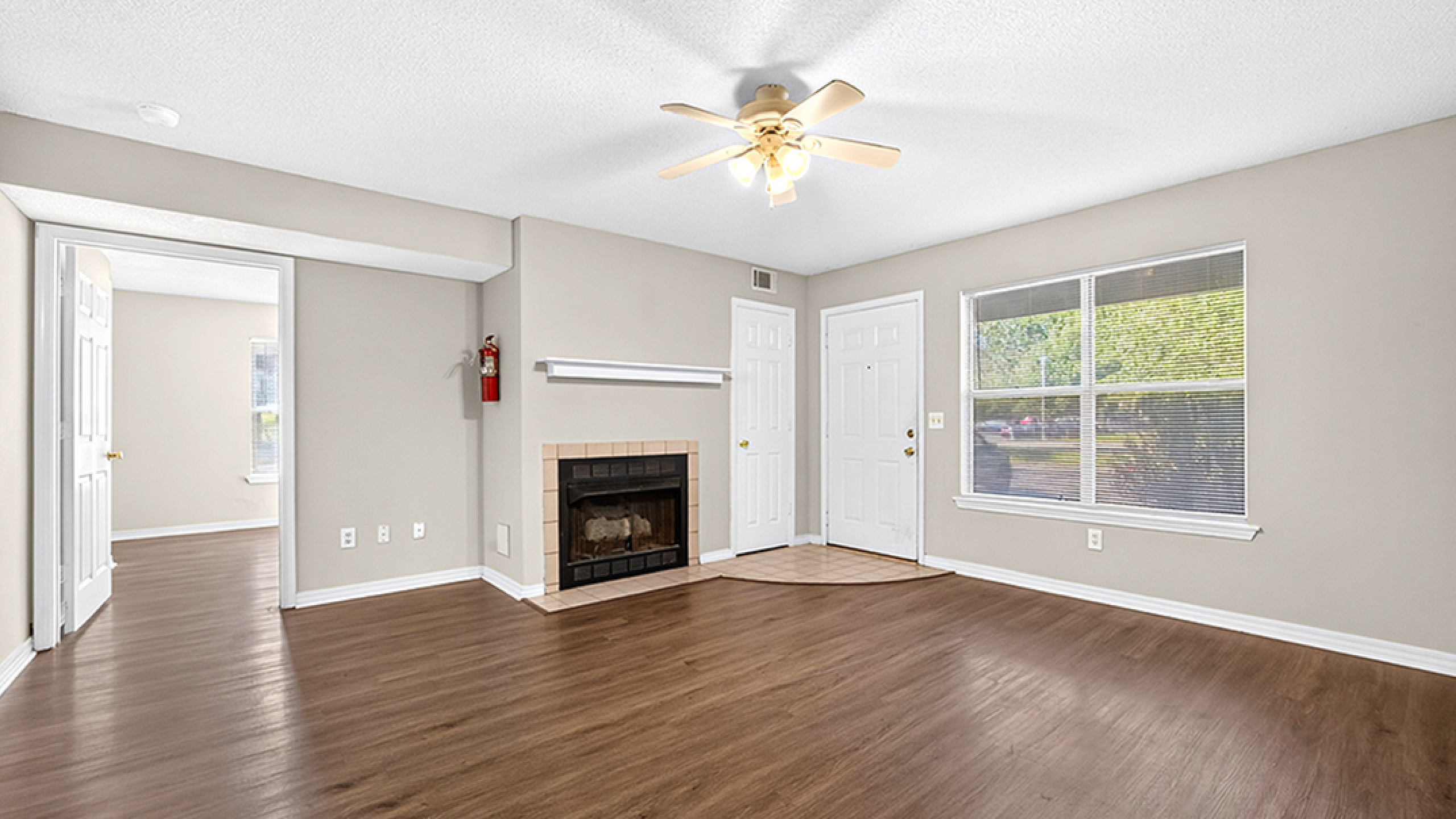 Bright and inviting living room with elegant wood flooring, cozy fireplace, and ample natural light from large windows.
