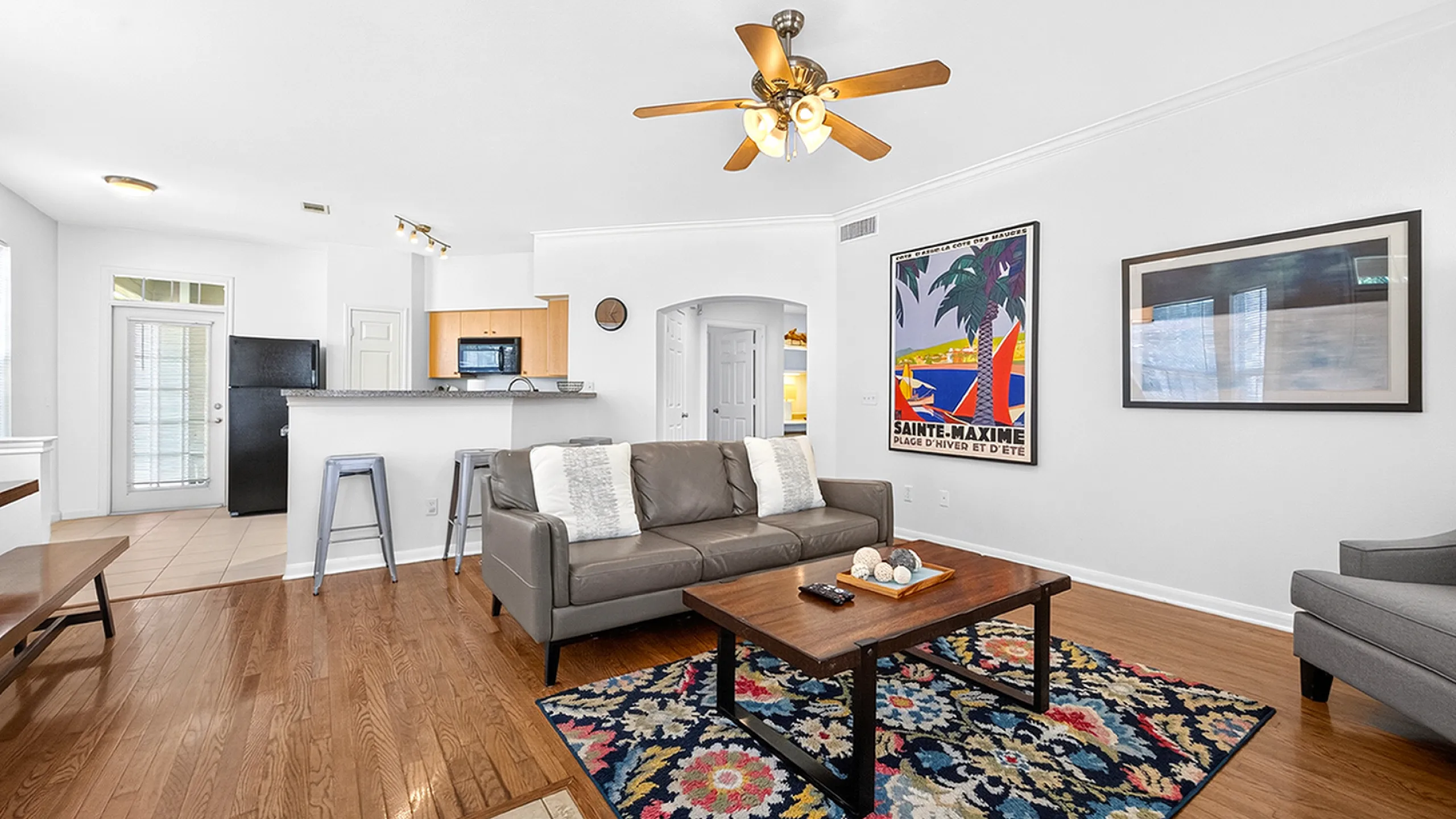 Inviting open-plan living room with elegant wood flooring, cozy seating nook, and modern kitchen bar area.