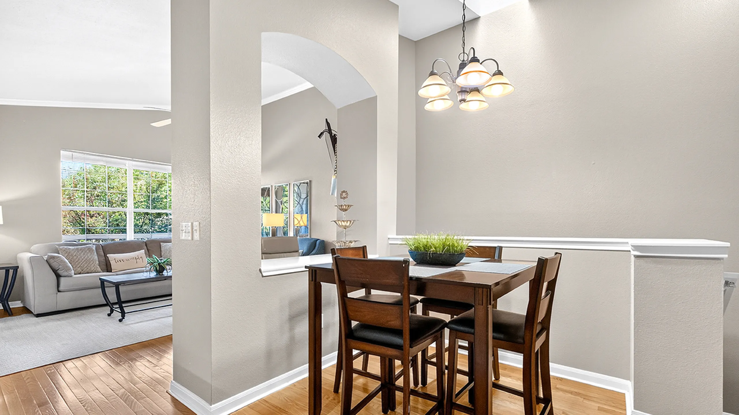 Elegant open-plan dining area with stylish wooden furniture and cozy living room, featuring abundant natural light and soft neutral tones.
