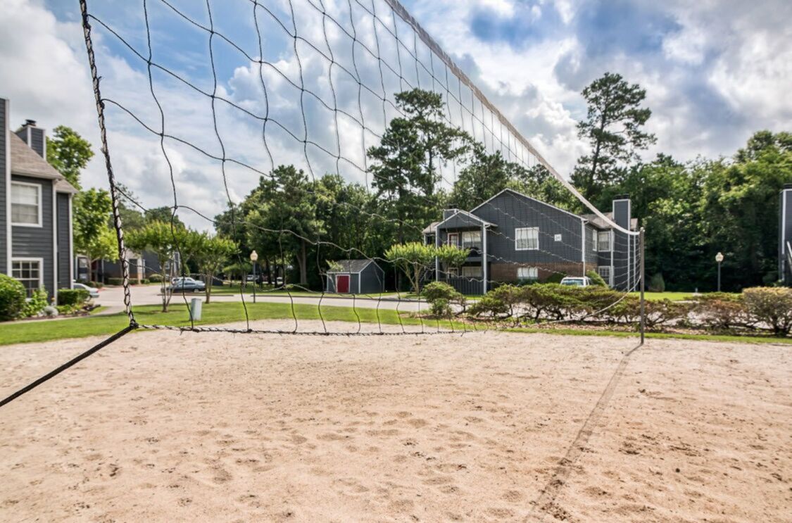 Inviting sandy volleyball court surrounded by lush greenery and modern apartments, perfect for active outdoor living.
