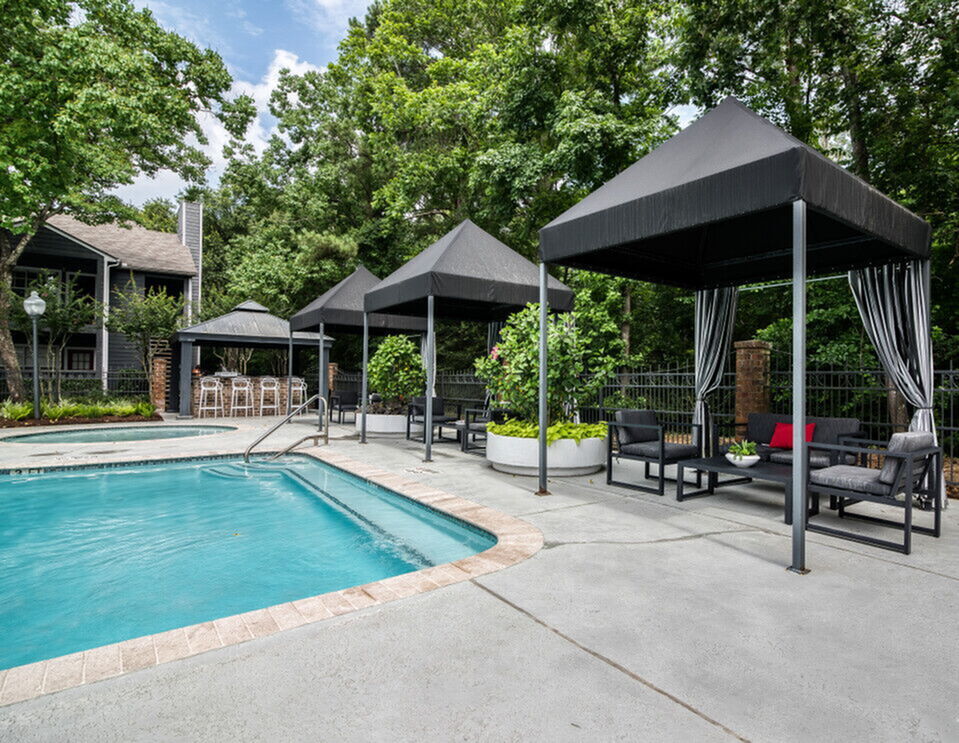 Elegant outdoor pool area with stylish canopies, lush greenery, and modern lounge seating, perfect for relaxation and gatherings.