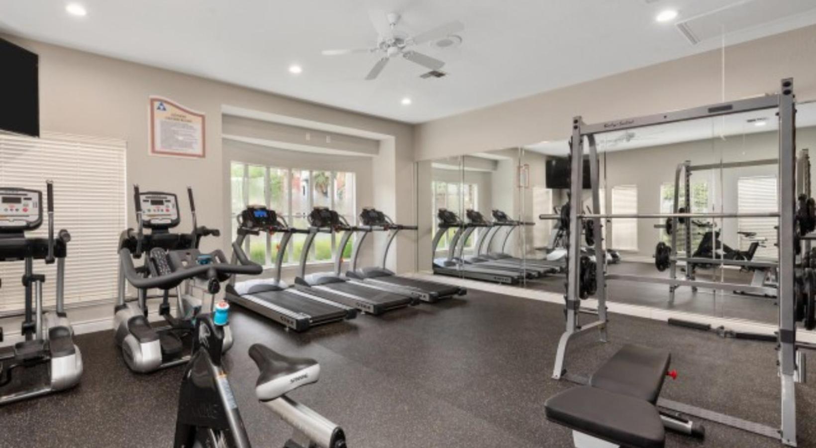 Modern apartment gym featuring state-of-the-art treadmills, exercise bikes, and weightlifting equipment, perfect for fitness enthusiasts.