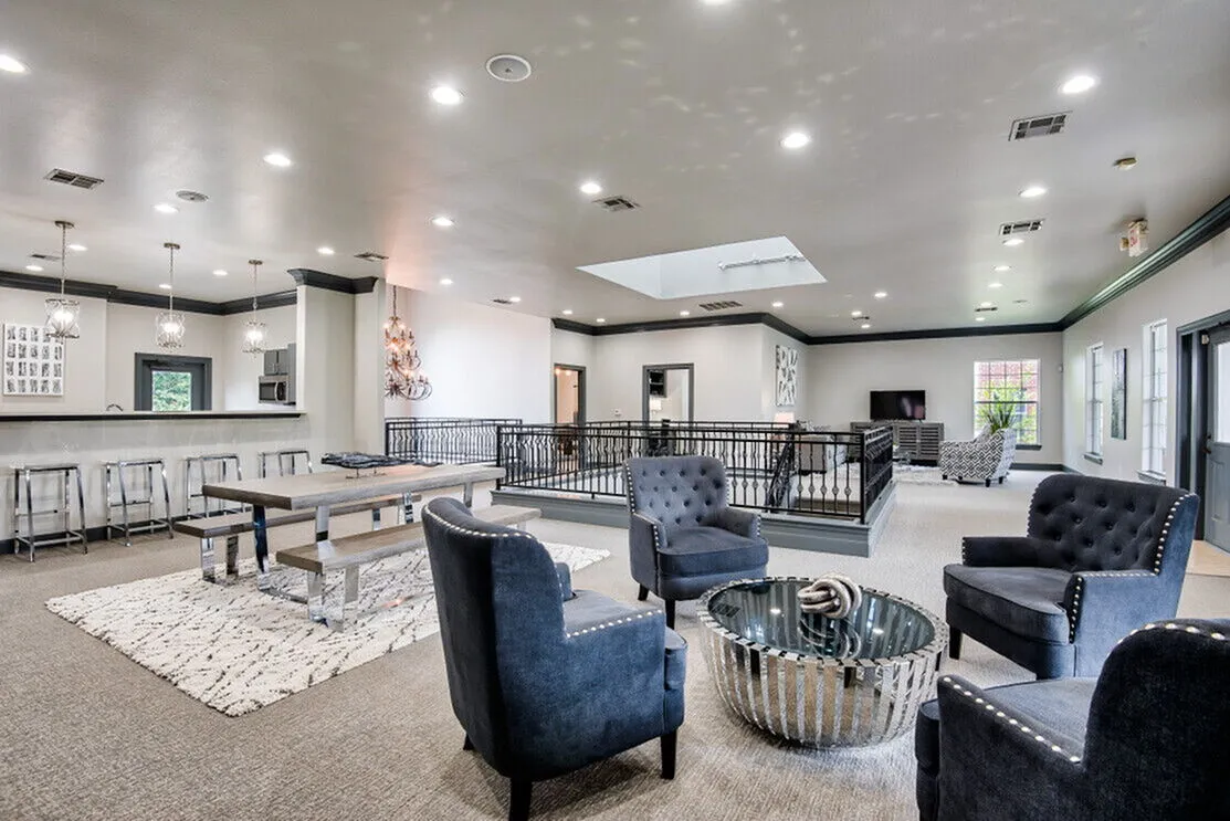 Spacious modern lounge area with elegant seating, stylish chandeliers, and an open-concept kitchen, perfect for relaxation and entertaining.