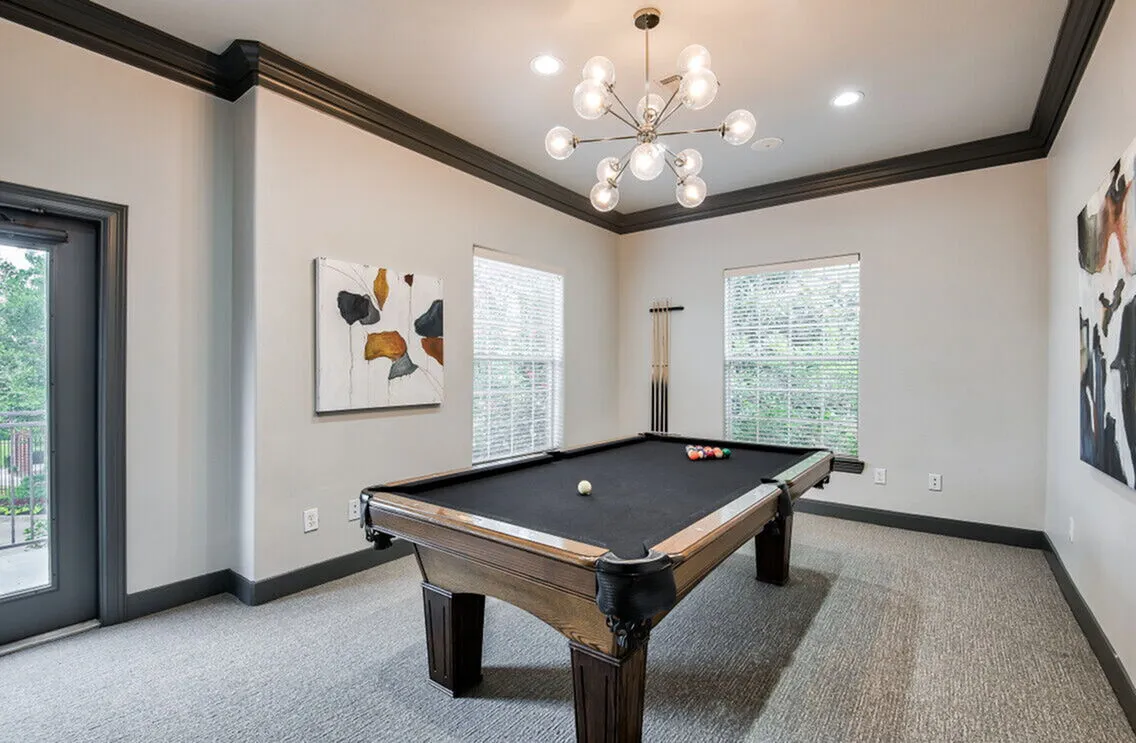 Chic apartment lounge featuring a sleek pool table under modern lighting, perfect for entertaining.