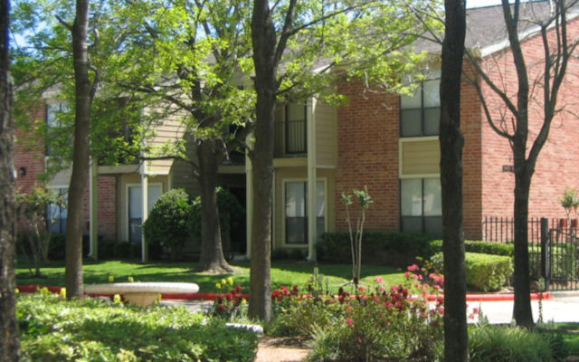 Charming brick apartment with lush greenery, vibrant flowers, and a serene outdoor setting.