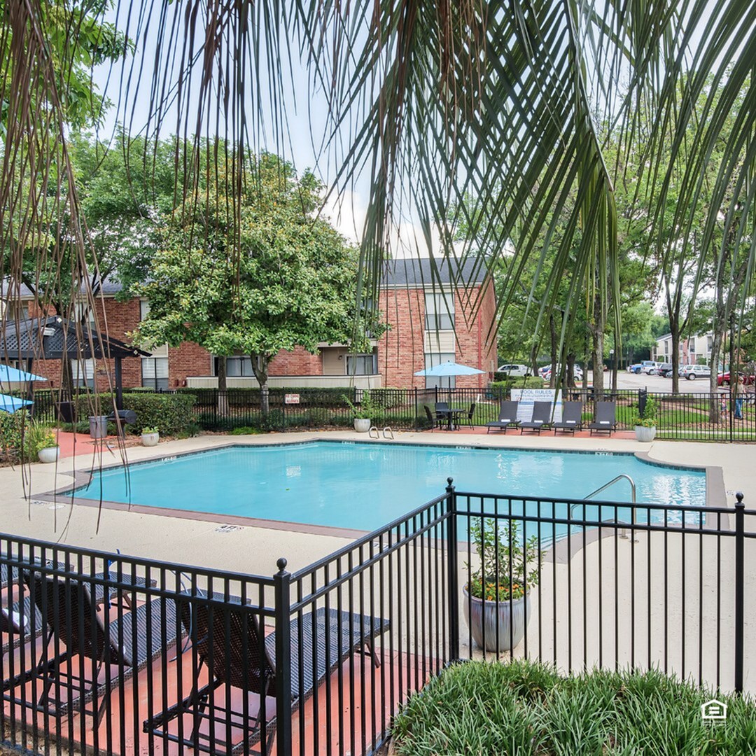 Charming community pool area with lush greenery, inviting lounge chairs, and a stylish fenced setting for relaxation.