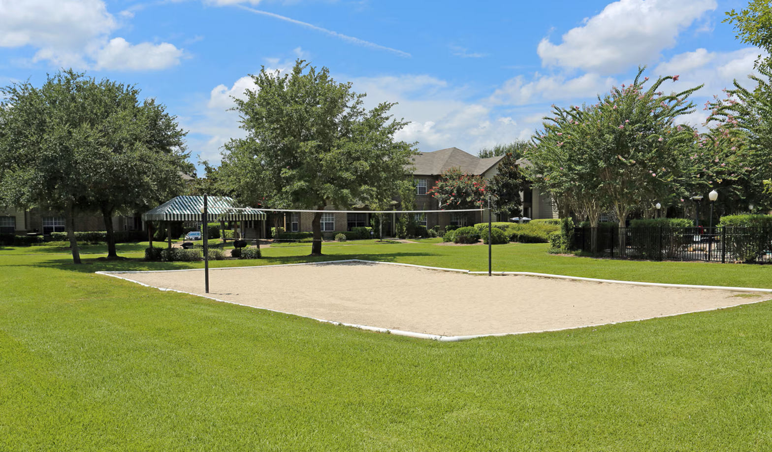 Expansive outdoor lounge area featuring a volleyball court and lush greenery, perfect for recreation and relaxation.